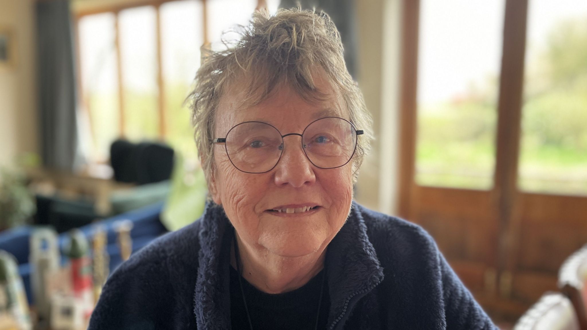 Local resident Lesley Bennett smiling wearing large round glasses with a thin black rim