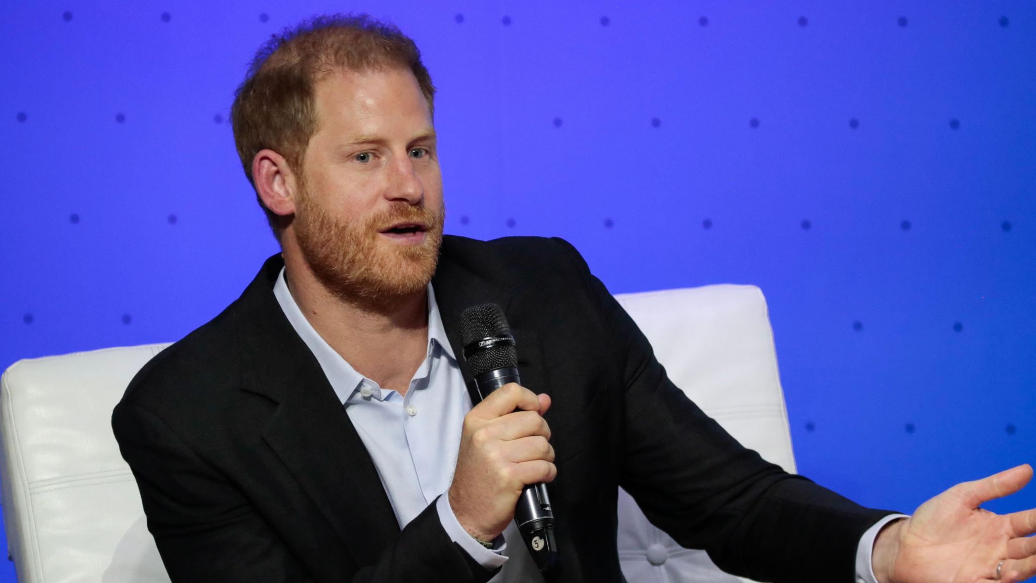 Prince Harry speaks into a microphone while sitting on a chair (file photo)