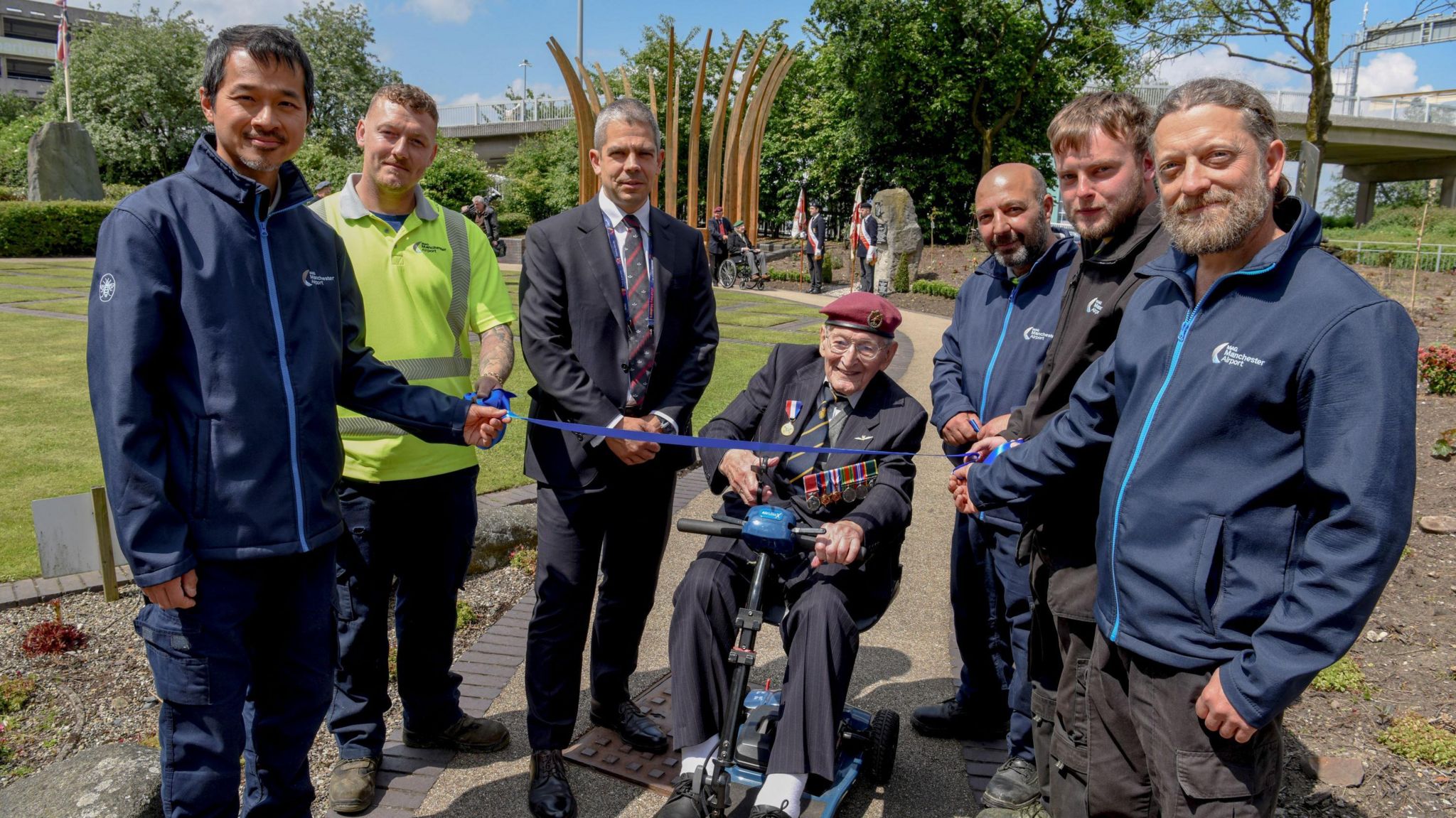 World War Two veteran Peter Davies cuts a ribbon on a new memorial garden with airport staff