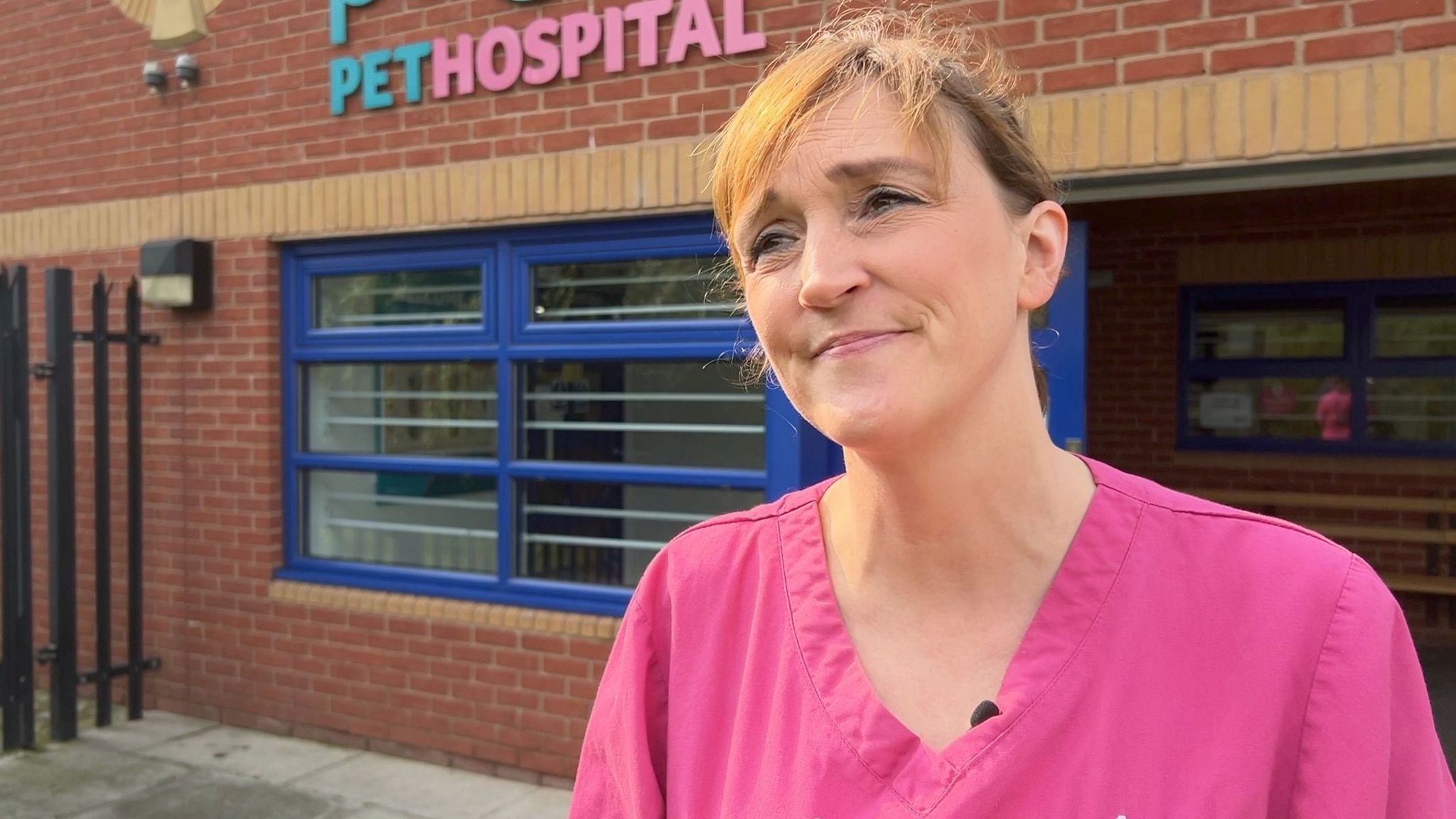 Nina Downing wearing pink scrubs and stood in front of a pet hospital