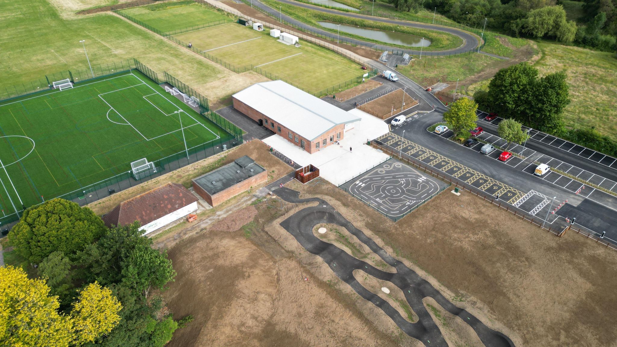 An aerial view of  a football pitch, pavilion and cycle track