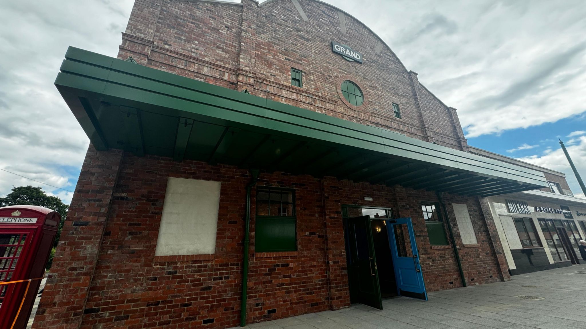Ryhope's Grand Cinema, rebuilt at Beamish, is a brown-bricked building with a green canopy above blue doors.