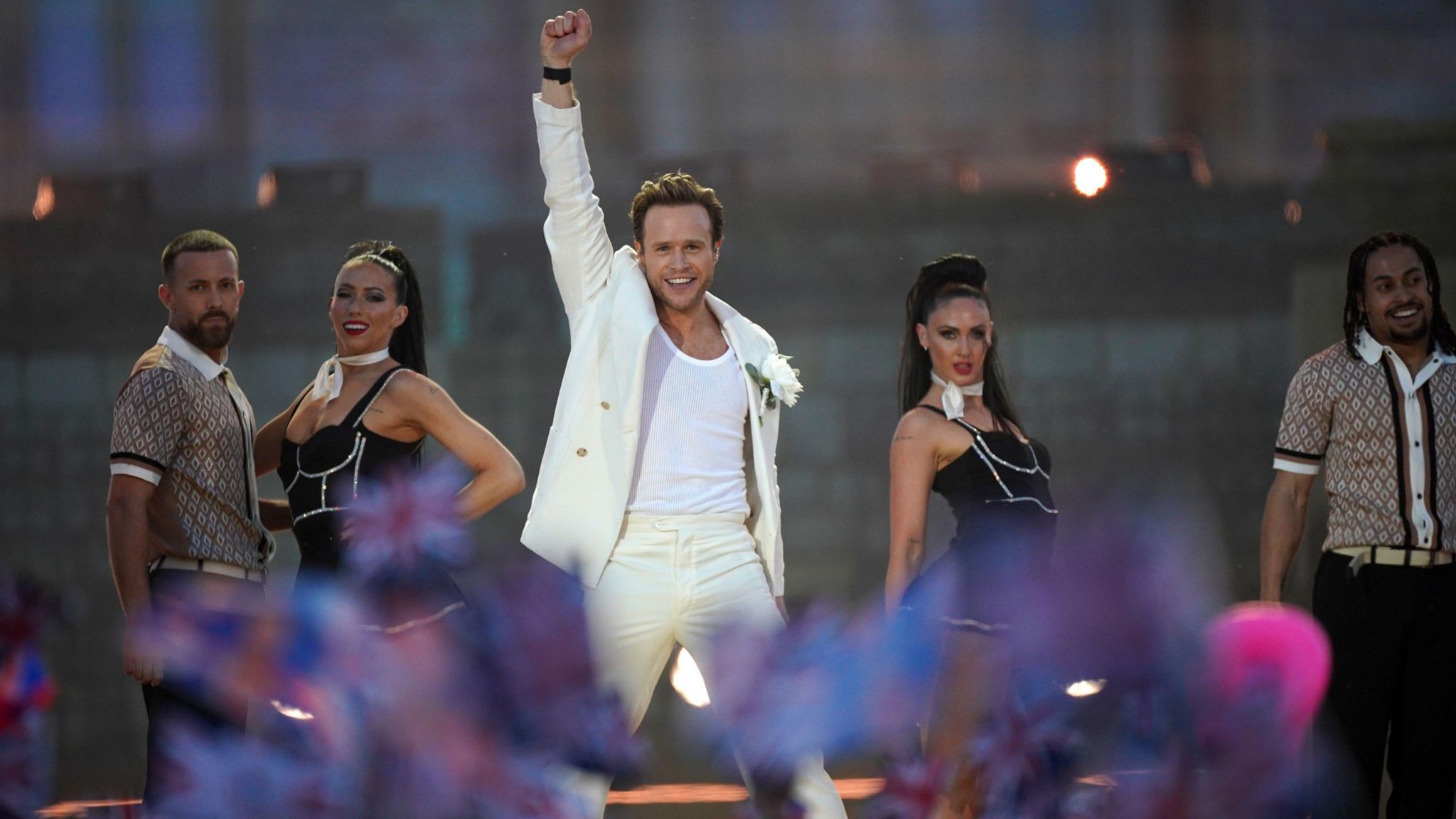 Olly Murs performing on stage with his fist in the air alongside four dancers