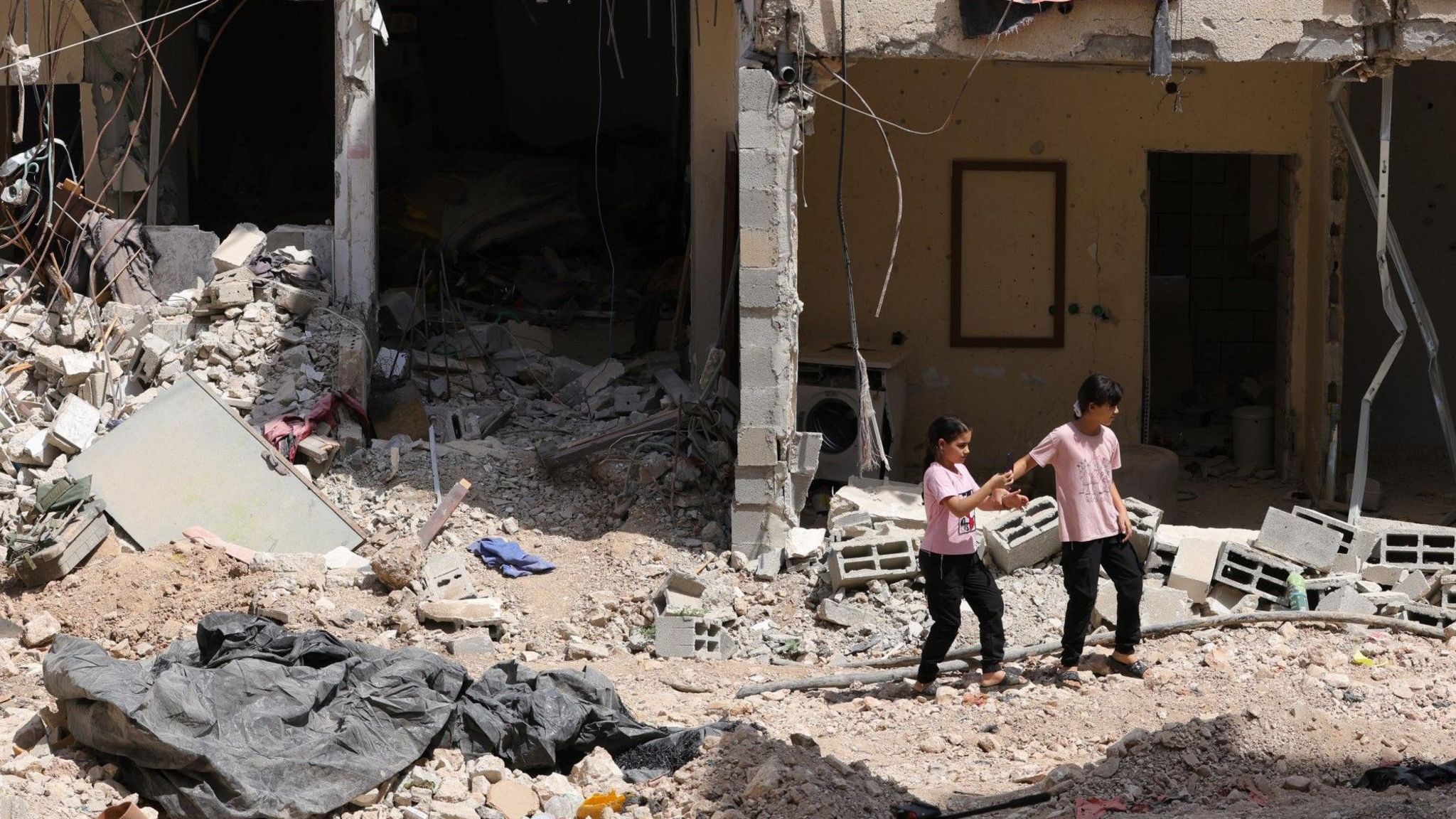 Palestinian girls walk on the rubble of damaged buildings and tarmac in Nur Shams refugee camp, in the occupied West Bank, after a two-day Israeli military operation (30 August 2024)