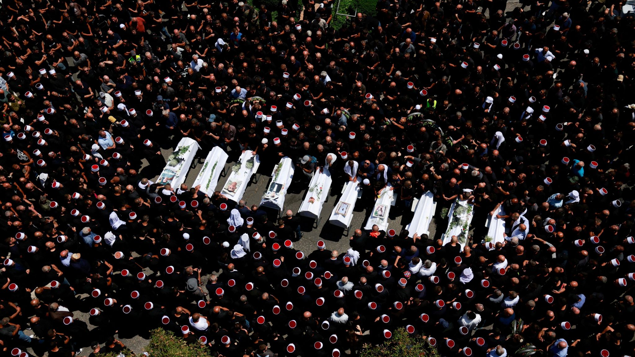 Mourners surround 10 of the coffins for children killed in strike