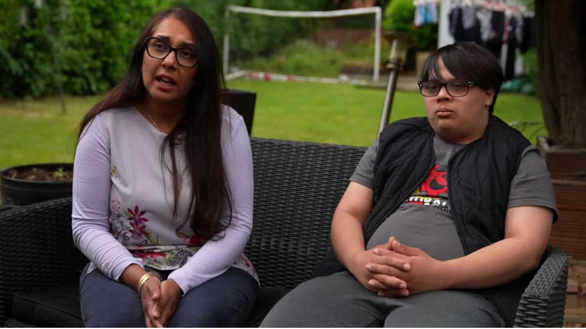 Ramandeep and her son Harry sitting on a bench in their garden, with the lawn behind