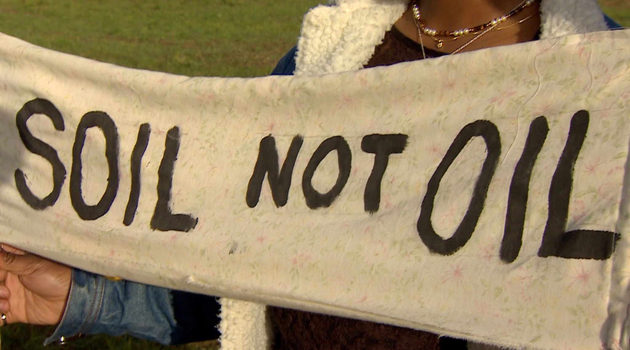 A protestor holding a sign stating 'soil not oil'