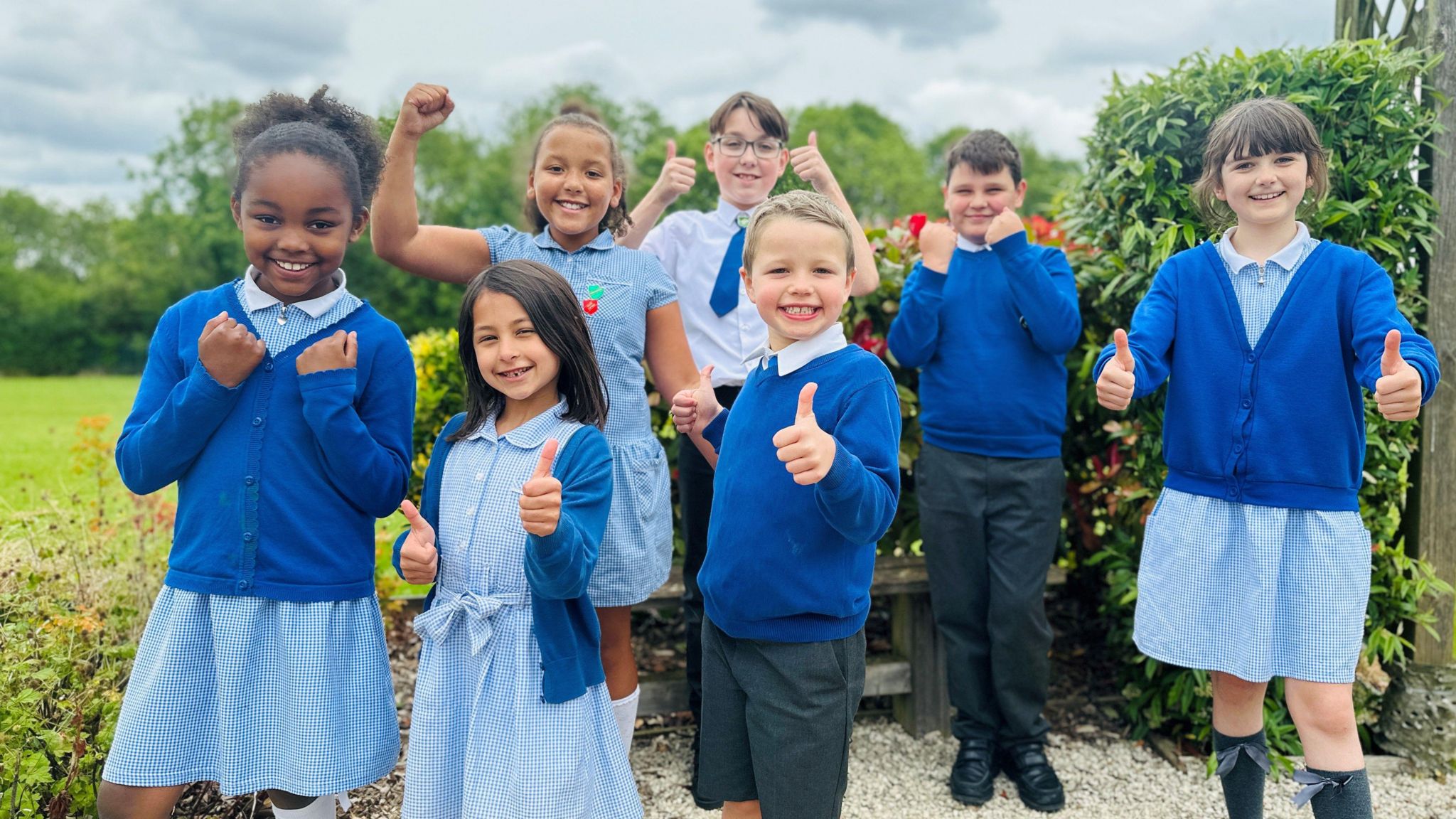 Children smiling and giving a thumbs up 