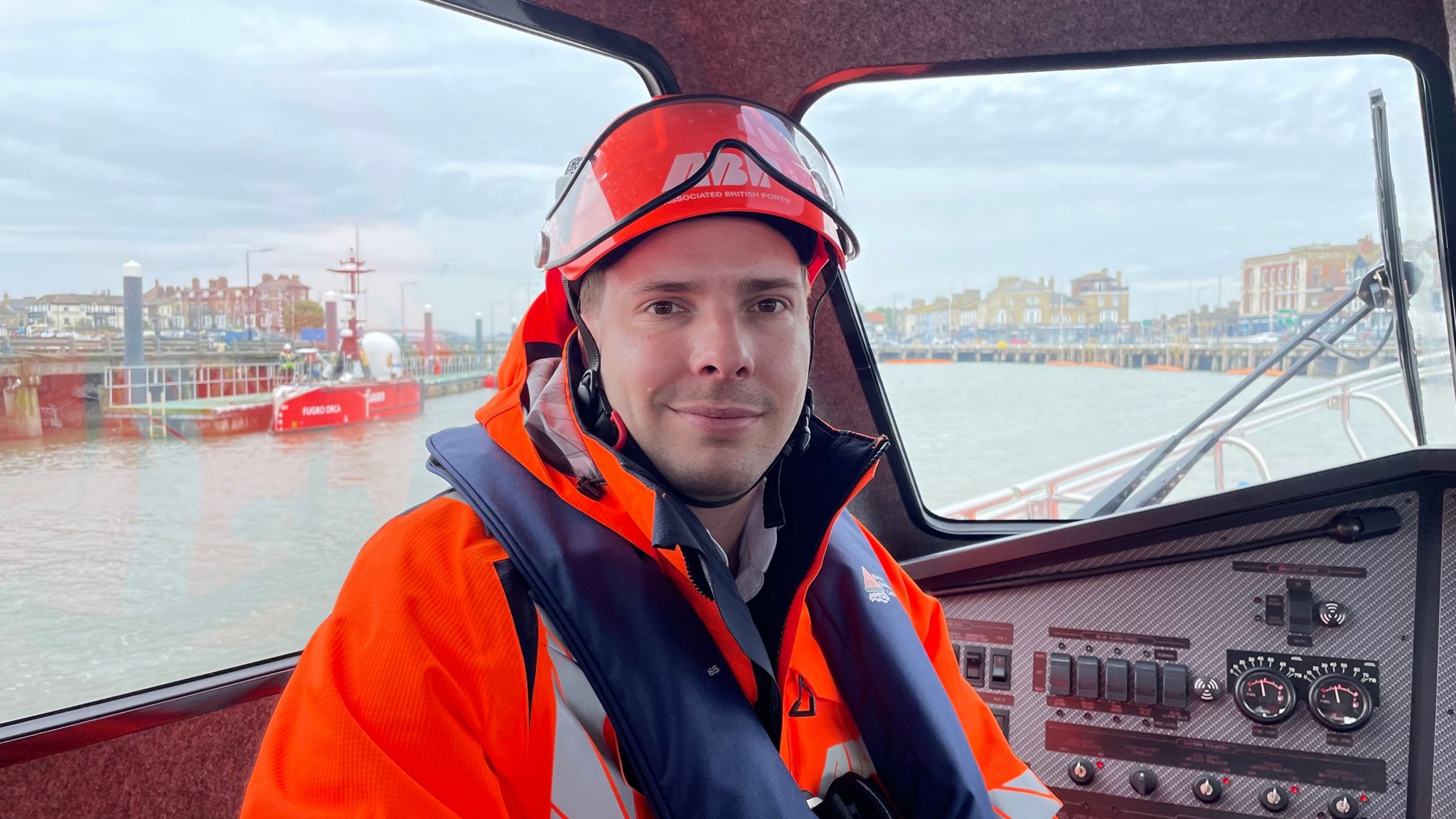 Tom Duit wearing high visibility clothing, a life jacket and helmet, sat inside a Port of Lowestoft pilot vehicle