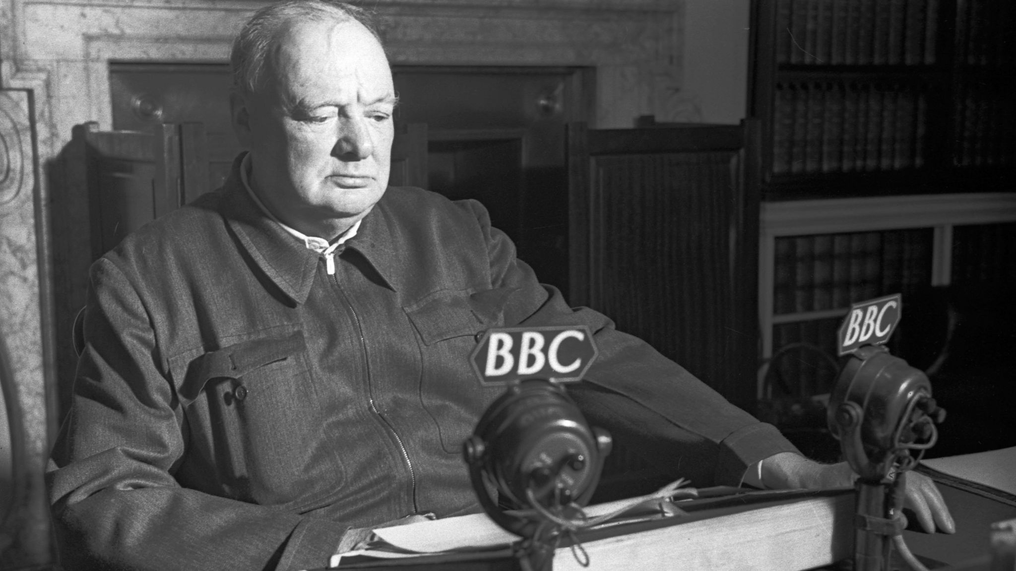 Winston Churchill sits in front of a BBC microphone during Second World War (1942) in a black and white image