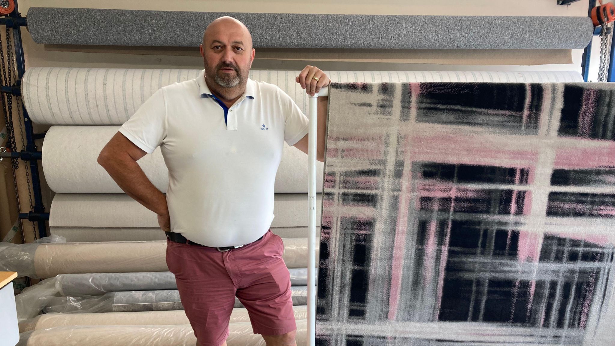 John Bull in his shop standing next to a big roll of carpet