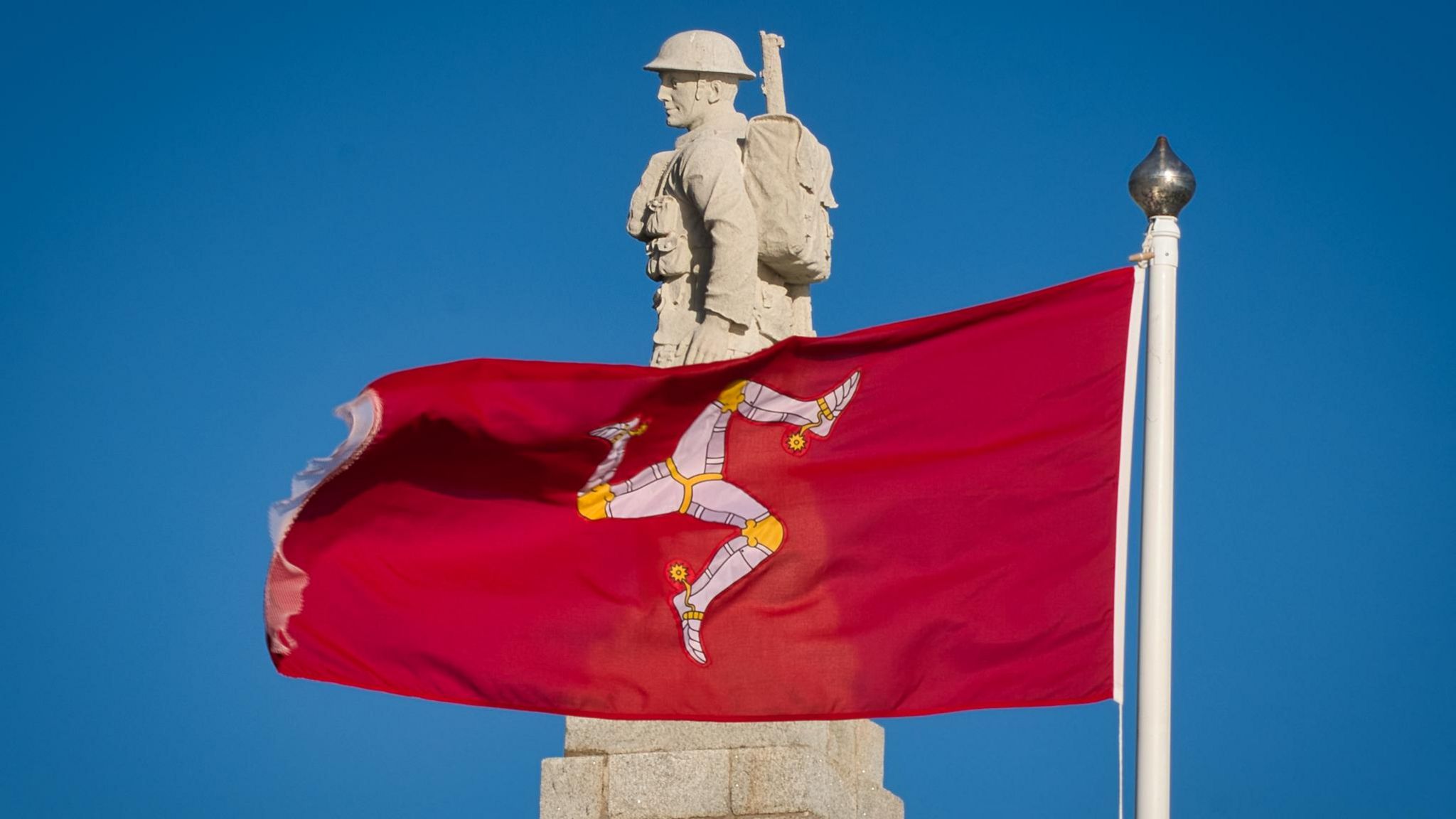 A Manx flag flying in front of the soldier on top of Douglas Promenade War Memorial