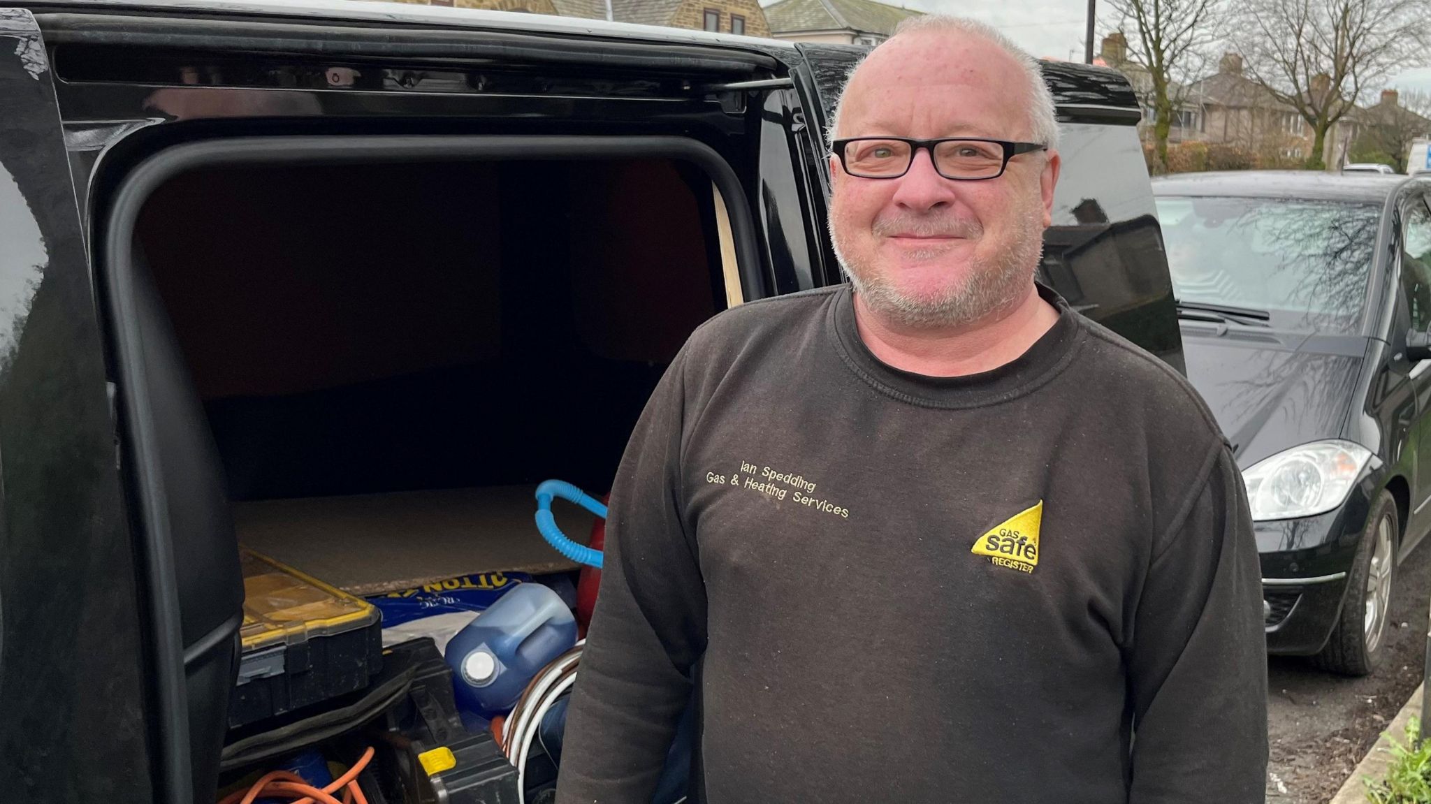 Ian Spedding, a gas engineer standing outside his van parked in a street