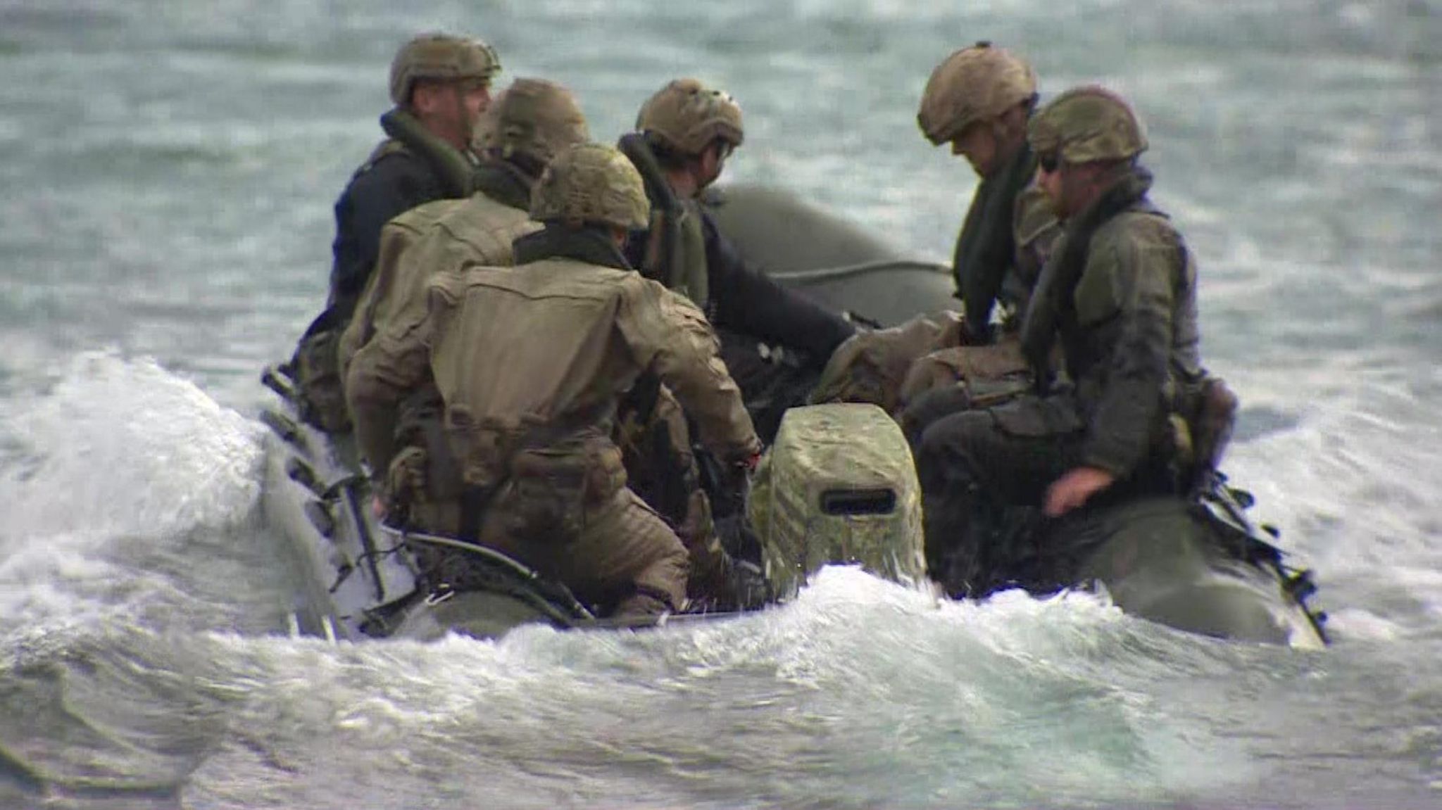 Six marines in a landing craft launching into the sea