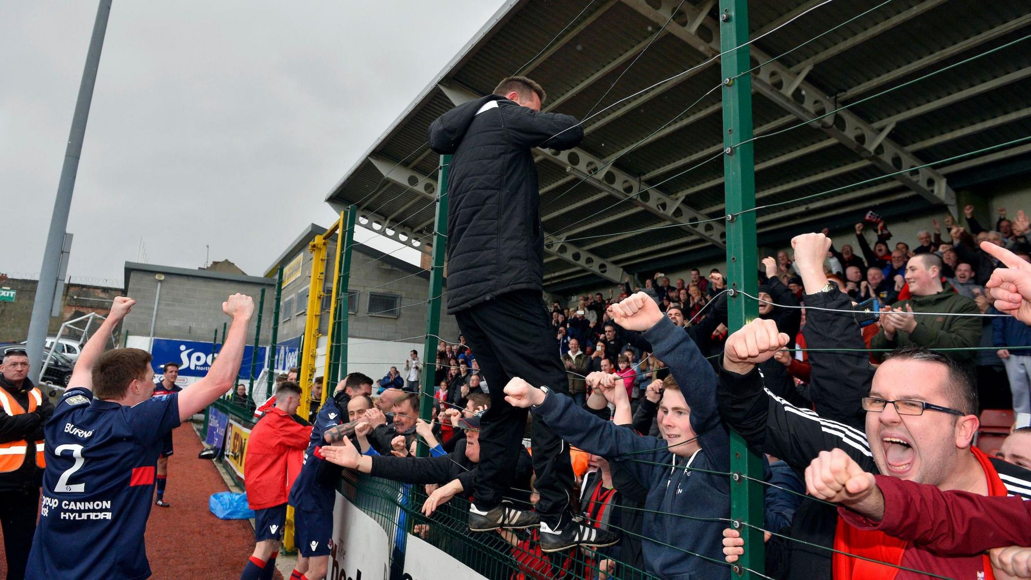 Stephen Baxter climbs the wire fence at Soltide after Crusaders clinched their first Irish Premiership title in 18 years