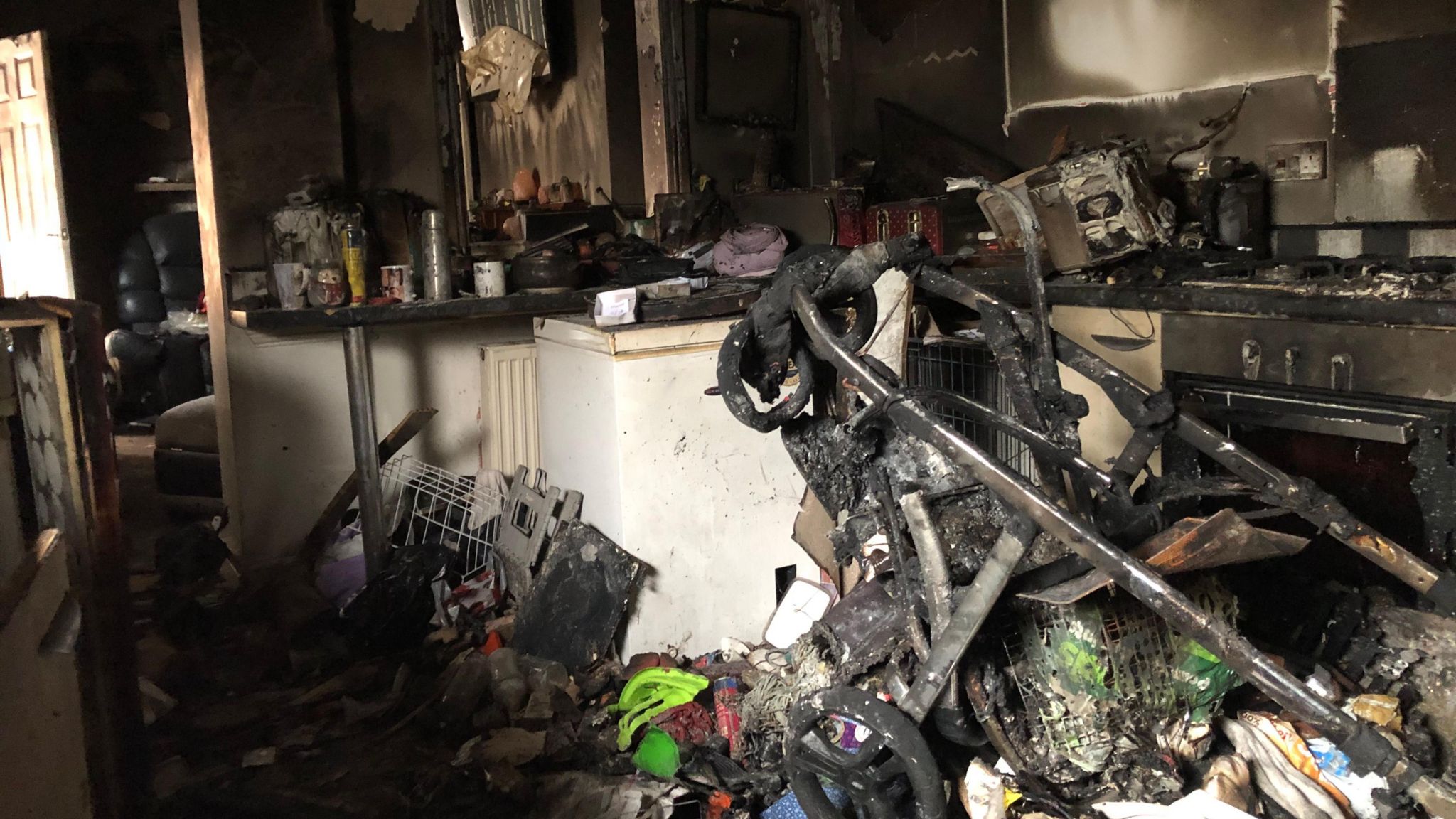 A melted pushchair stands among the debris 