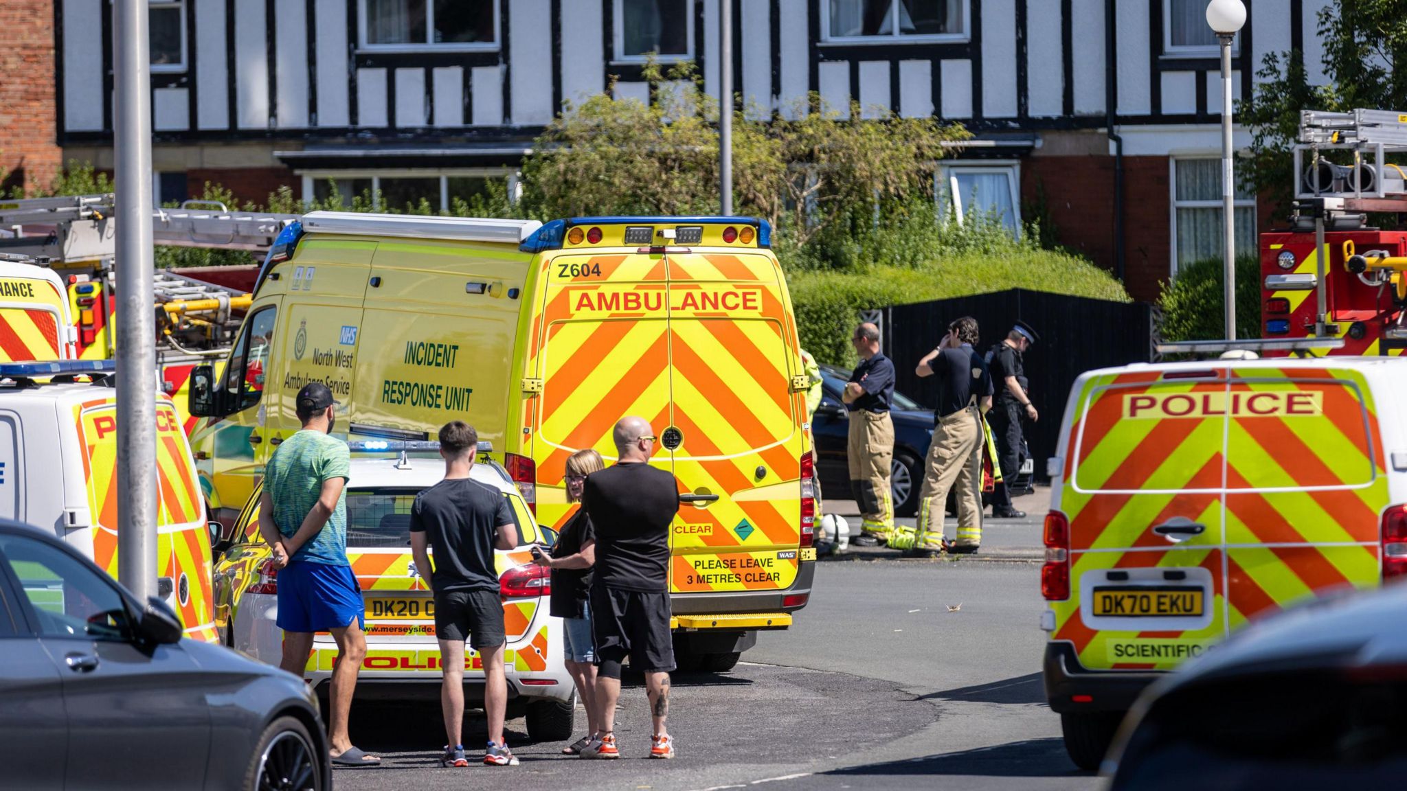 Locals look on as ambulance and police block the street 