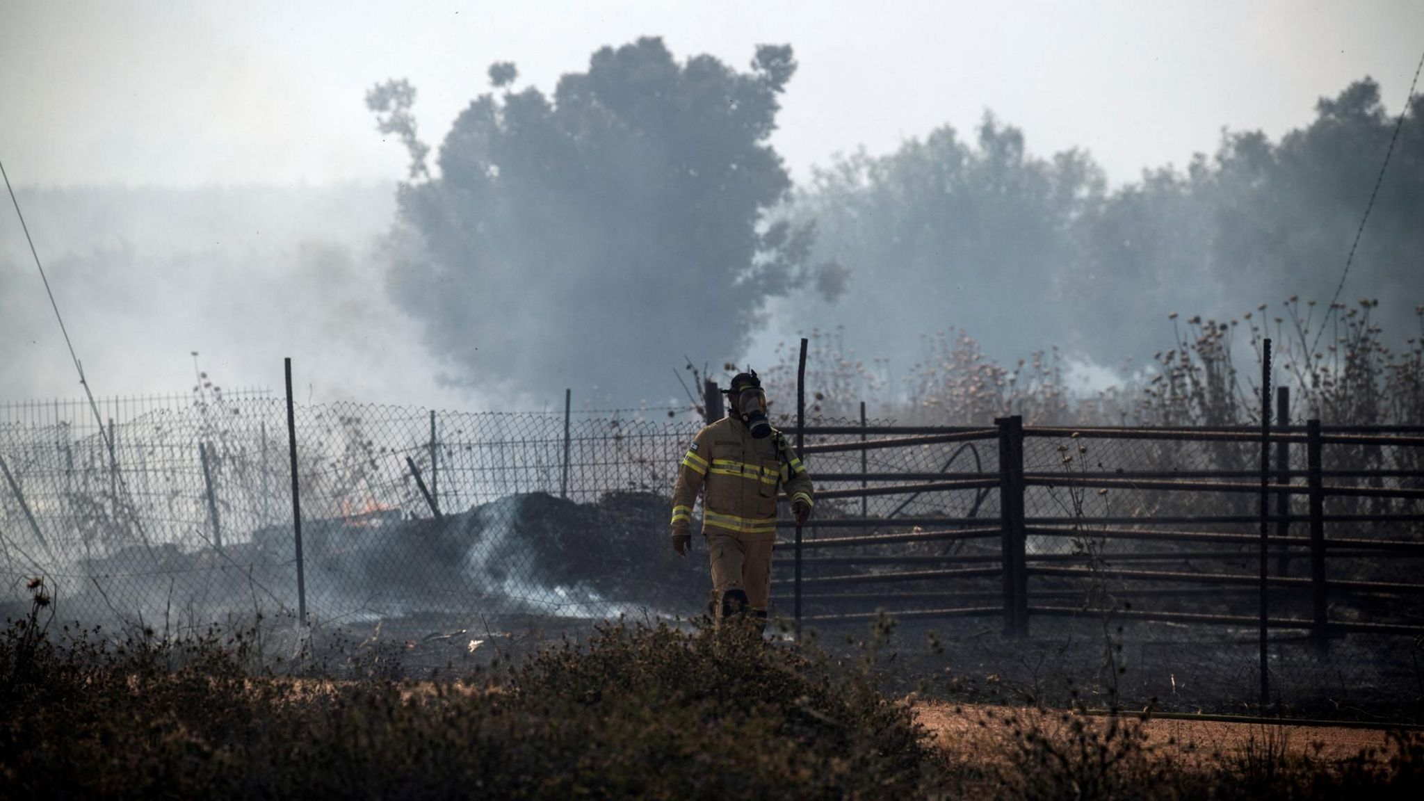 A fire-fighter walks past a blaze in northern Israel sparked by a Hezbollah rocket attack (12 June 2024)