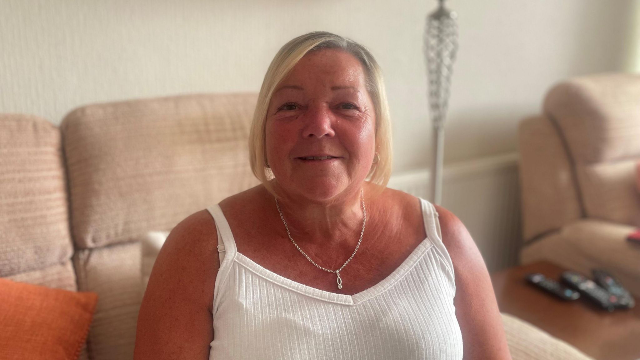 Woman sitting on sofa smiling at camera.