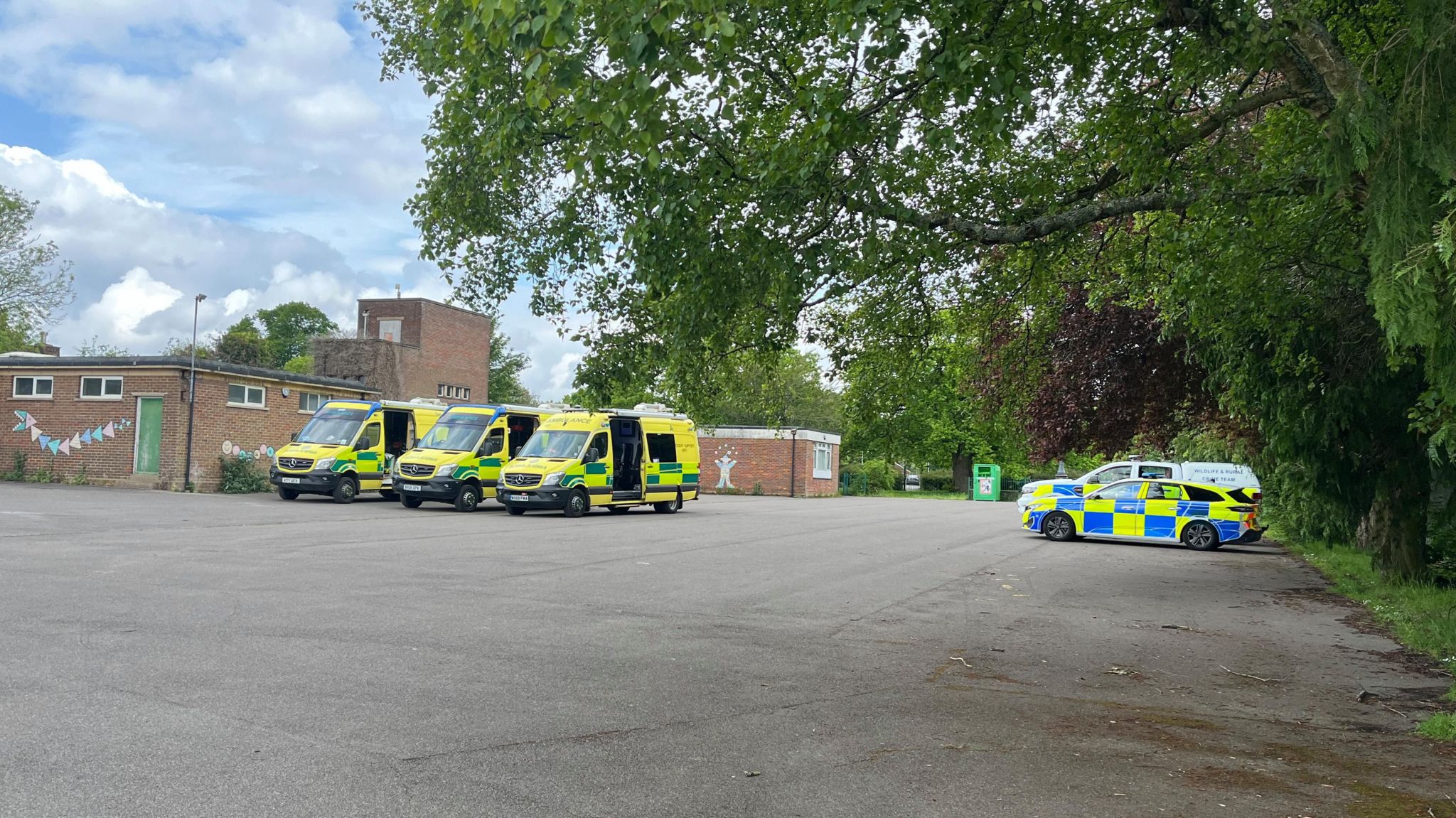 Emergency vehicles including ambulances and police cars parked on a school playground