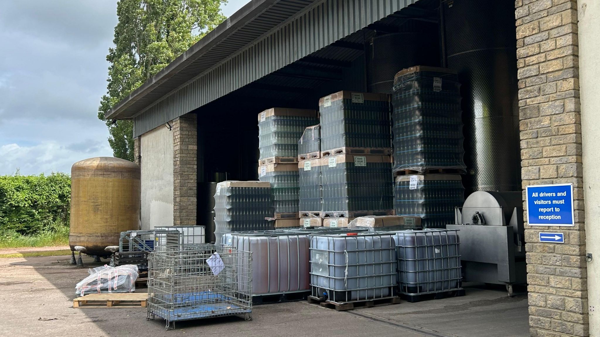 A warehouse shed full of crates of wine bottles and vats of wine