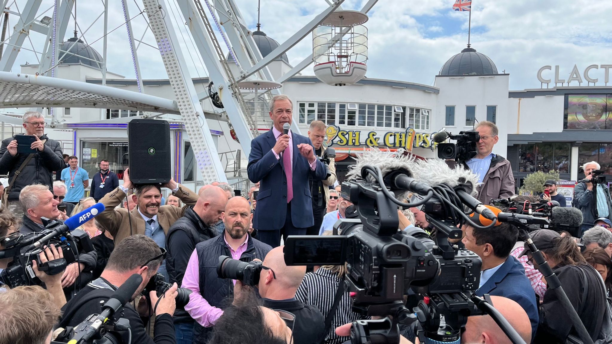 Nigel Farage talking to crowds with a microphone at Clacton Pier