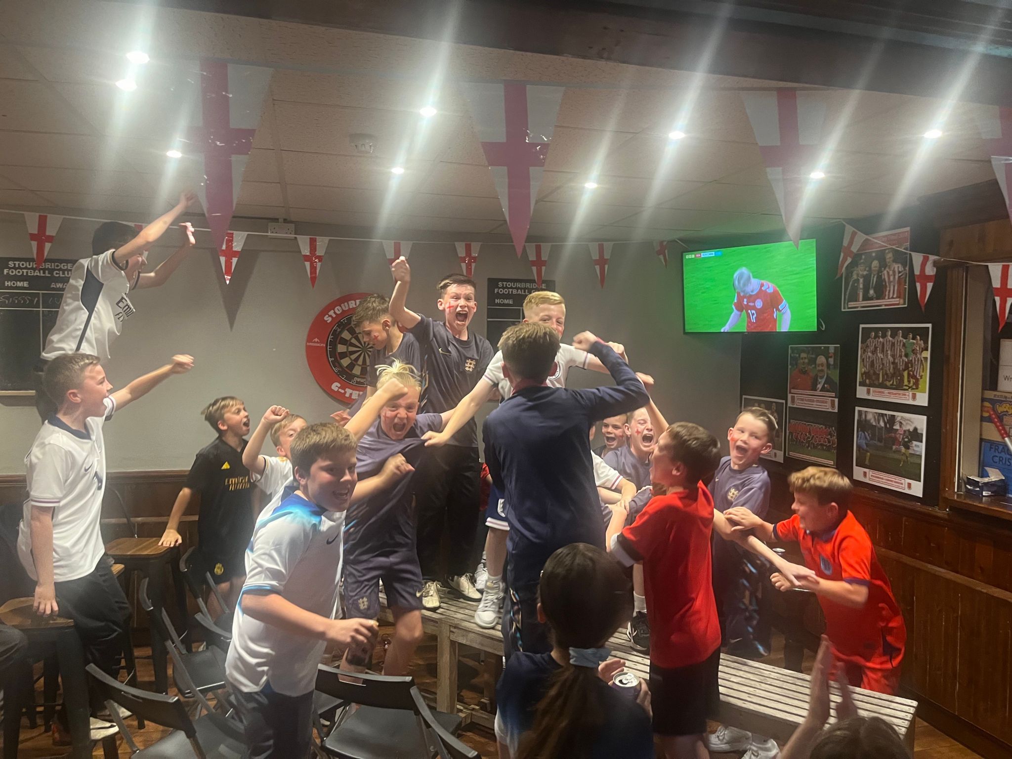 The children of Stourbridge cheer England's goal in front of a TV screen