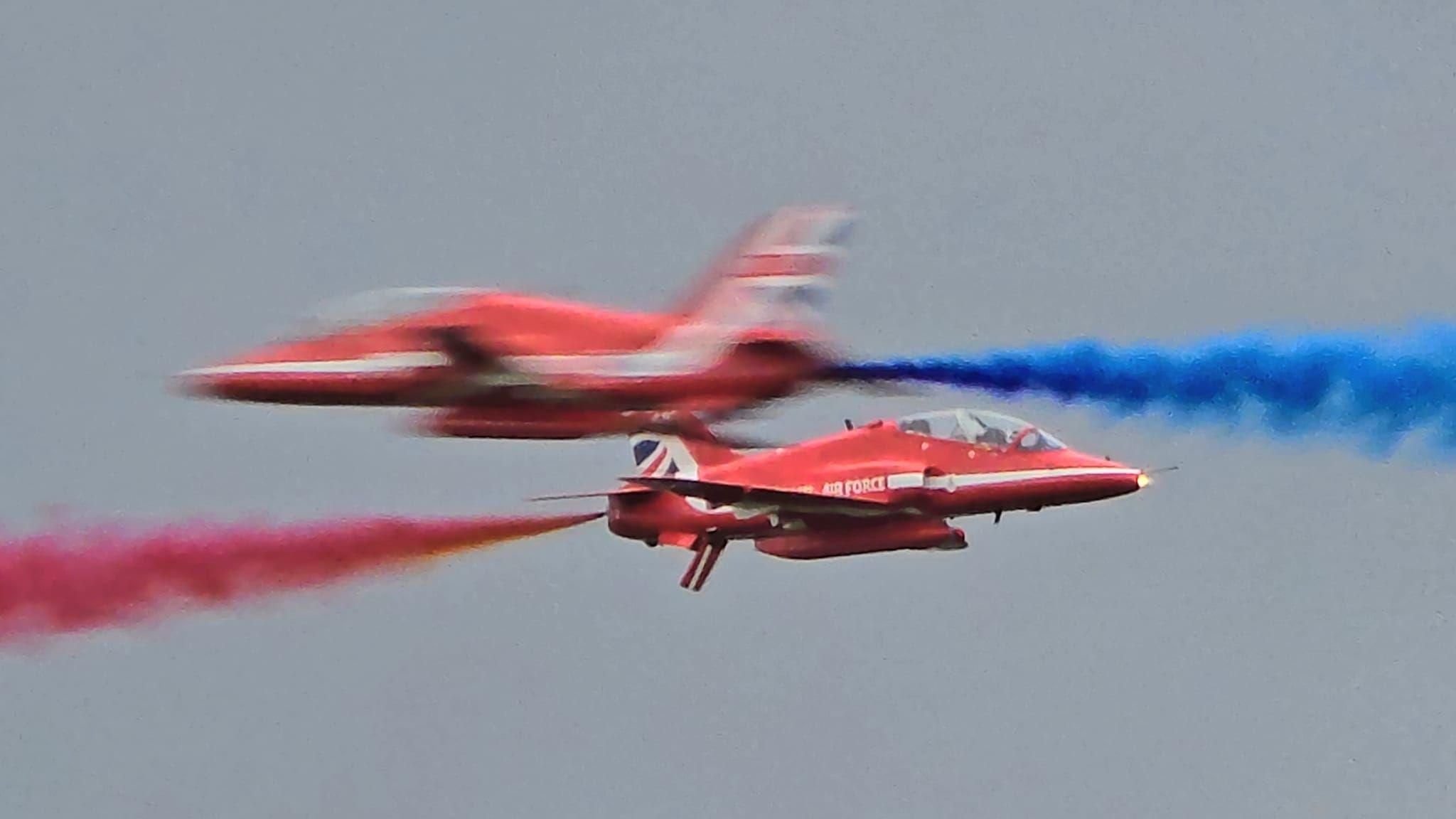 Two Red Arrow aircraft pass each other in the sky