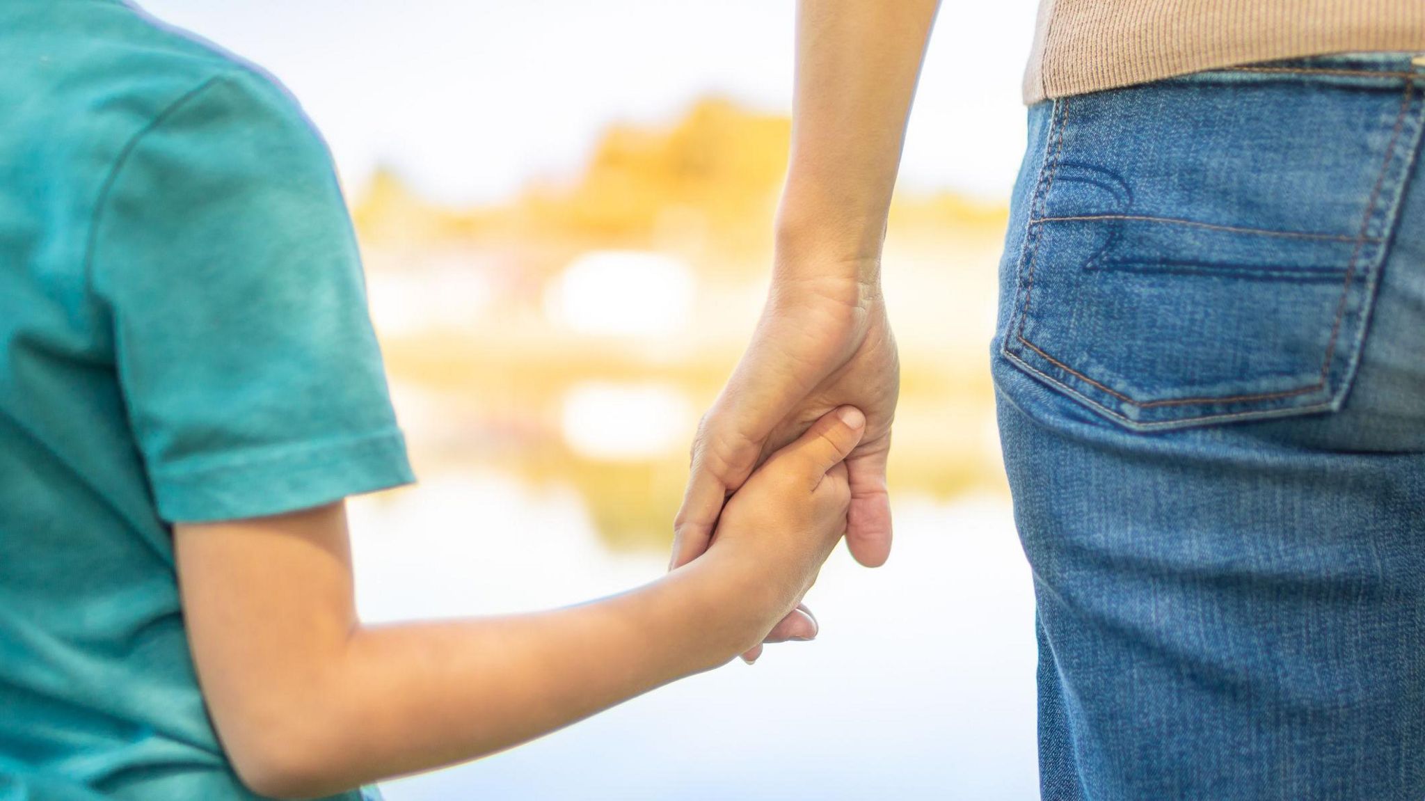 Child and woman from behind, close up of arms, holding hands