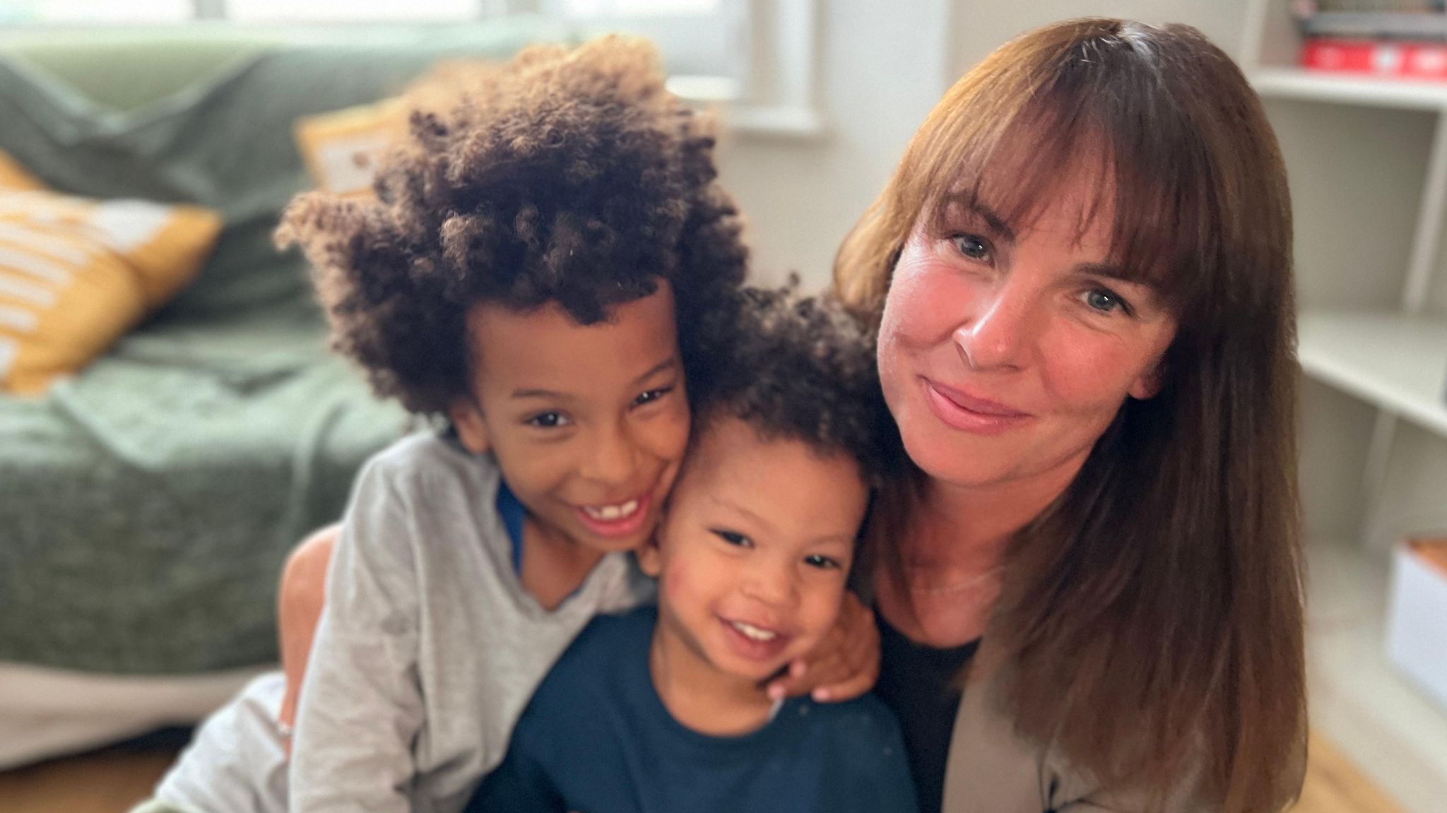 Laura Nwanya and her two sons cuddle together, smiling at the camera