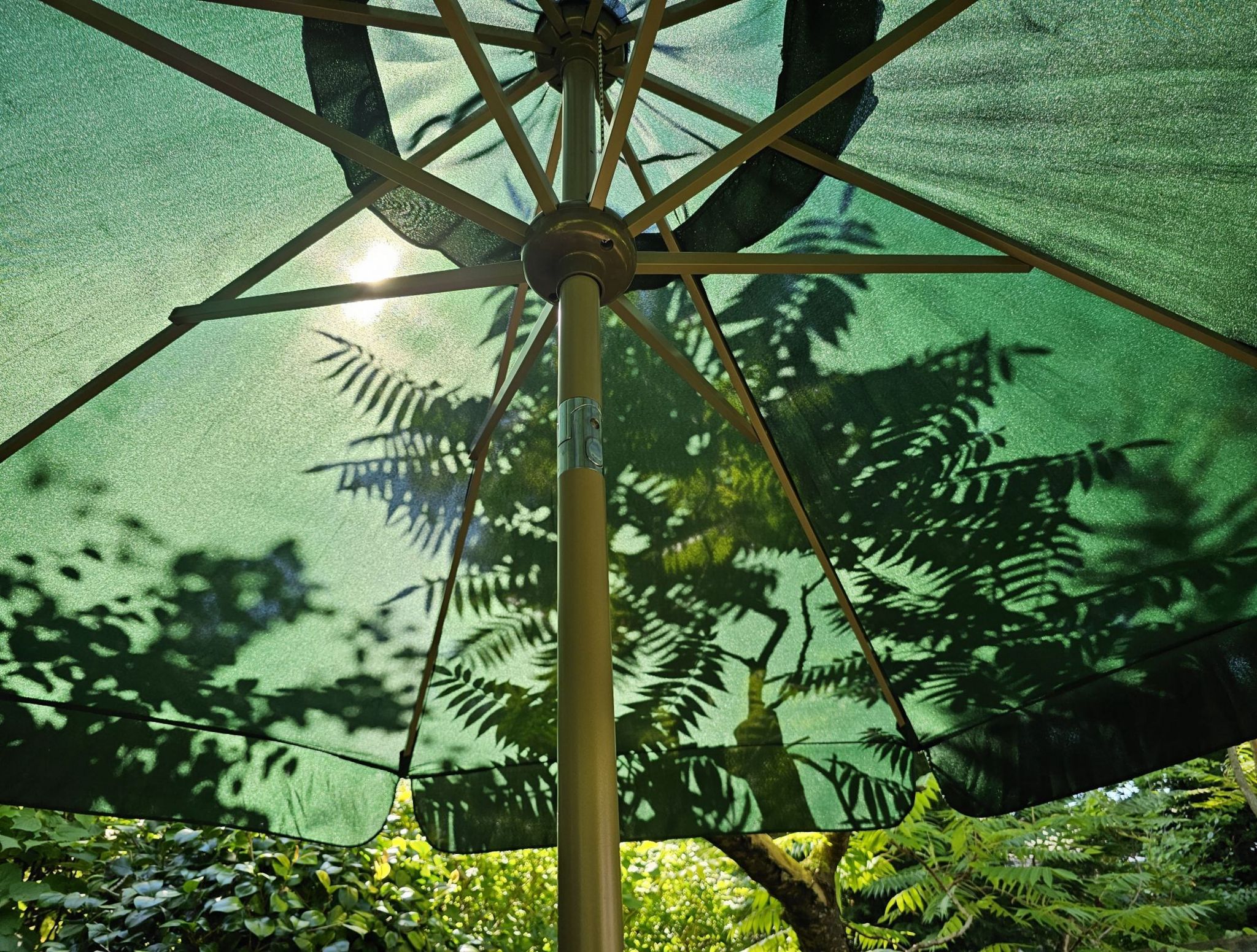 The view from underneath a parasol with trees behind