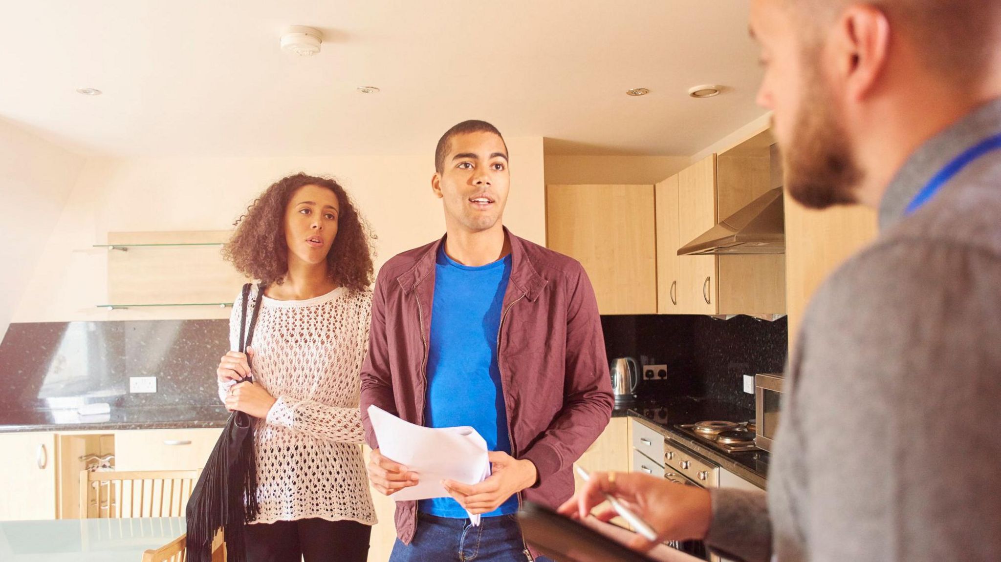 A woman and man talk to an estate agent while viewing a flat