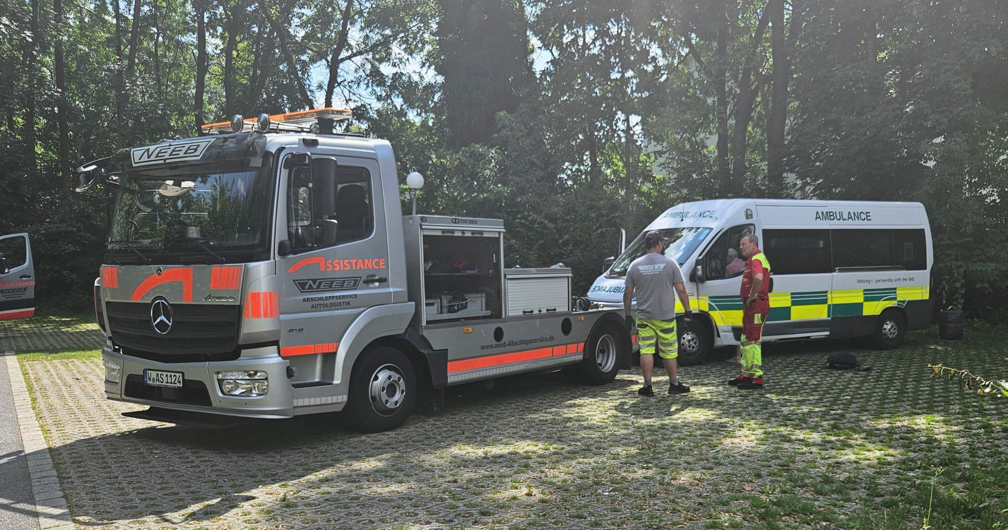 Ambulance being towed by grey and orange breakdown truck