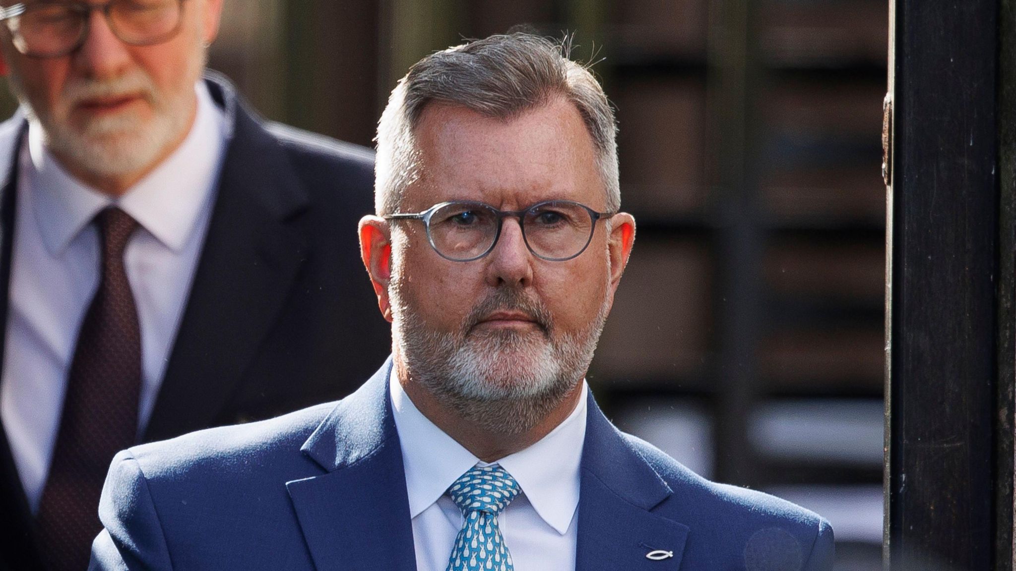 Sir Jeffrey Donaldson leaving Newry Crown Court, wearing glasses a blue suit and green tie. 