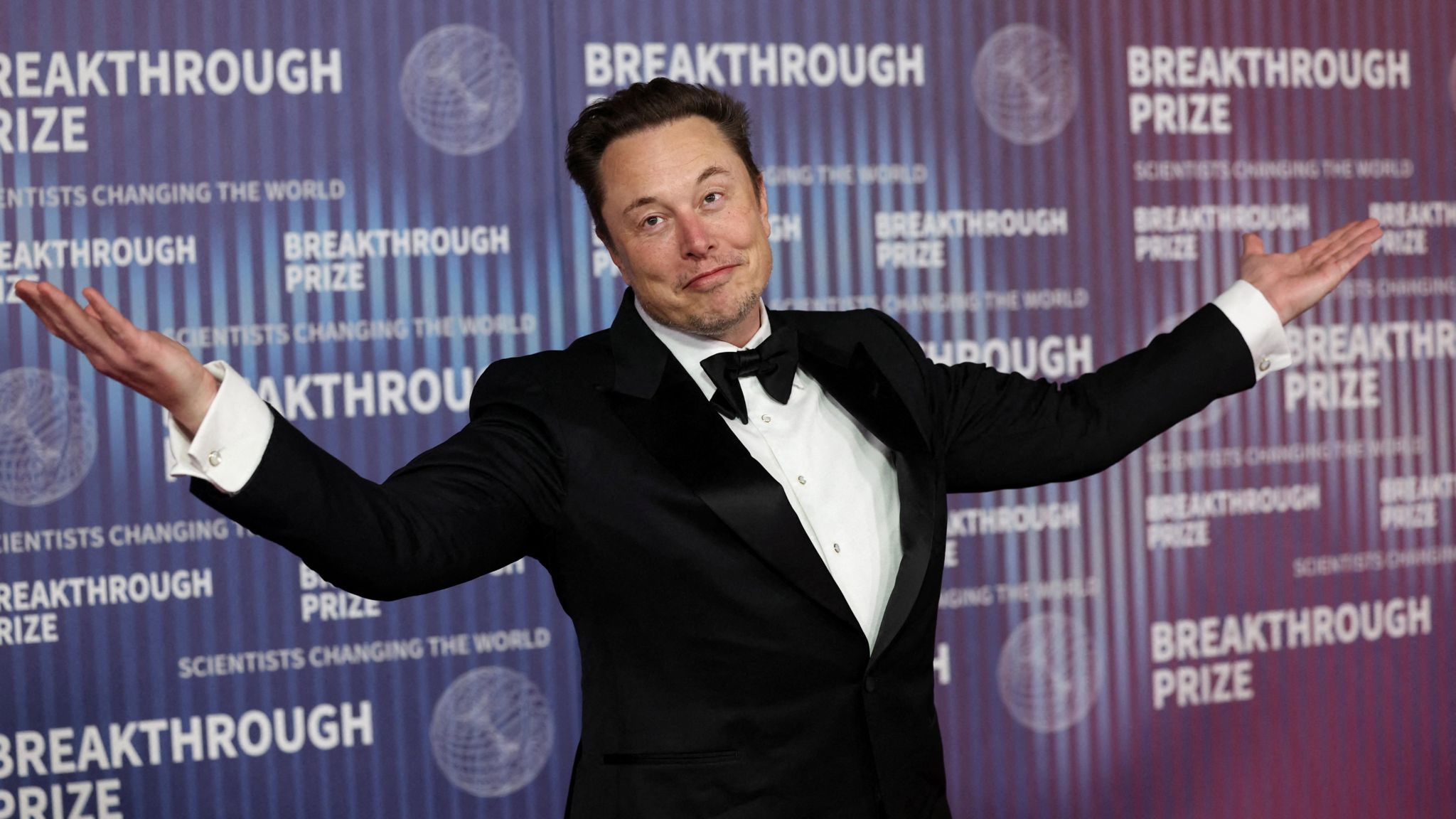 Elon Musk with his arms out wide
