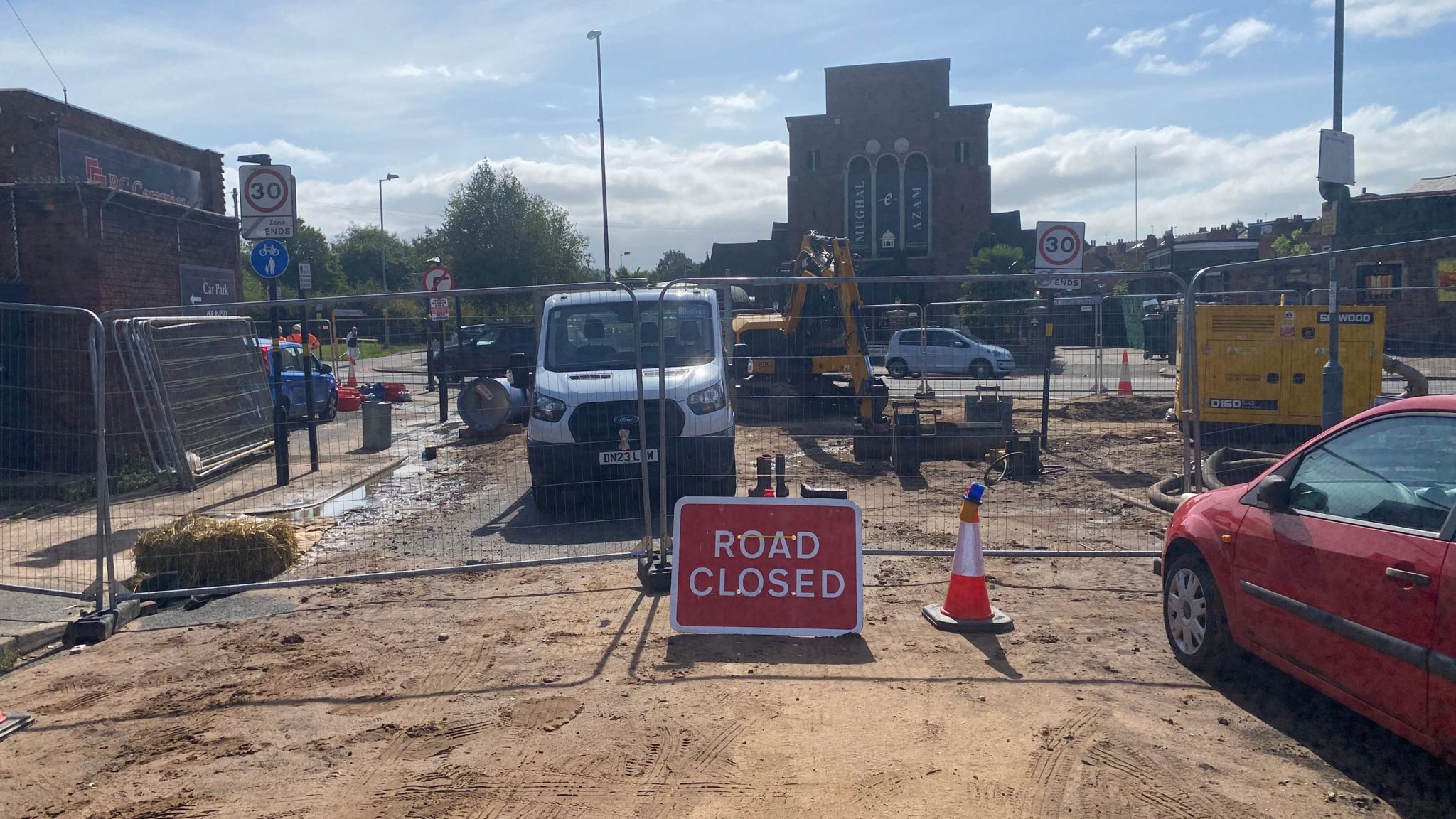 A road closed side with a building site in the background. Equipment can be seen as engineers are replacing a water main that burst. 