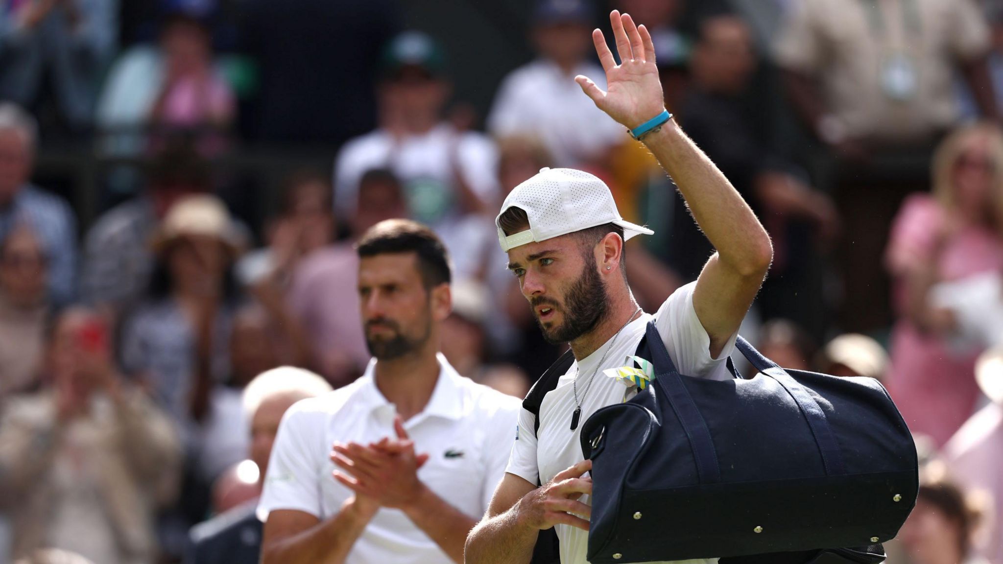 Jacob Fearnley is clapped off court by Novak Djokovic