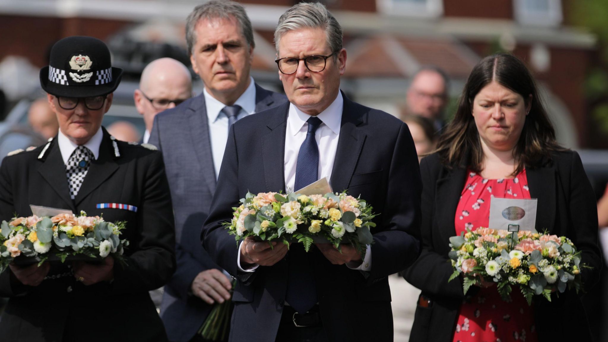 Merseyside Chief Constable Serena Kennedy, in full uniform, Liverpool City Region Mayor Steve Rotheram, in a grey suit, Prime Minster Sir Keir Starmer, in a black suit, and Merseyside Police and Crime Commissioner Emily Spurrell, in a red and black dress, carry floral wreaths to lay in tribute to those killed in the Southport attack