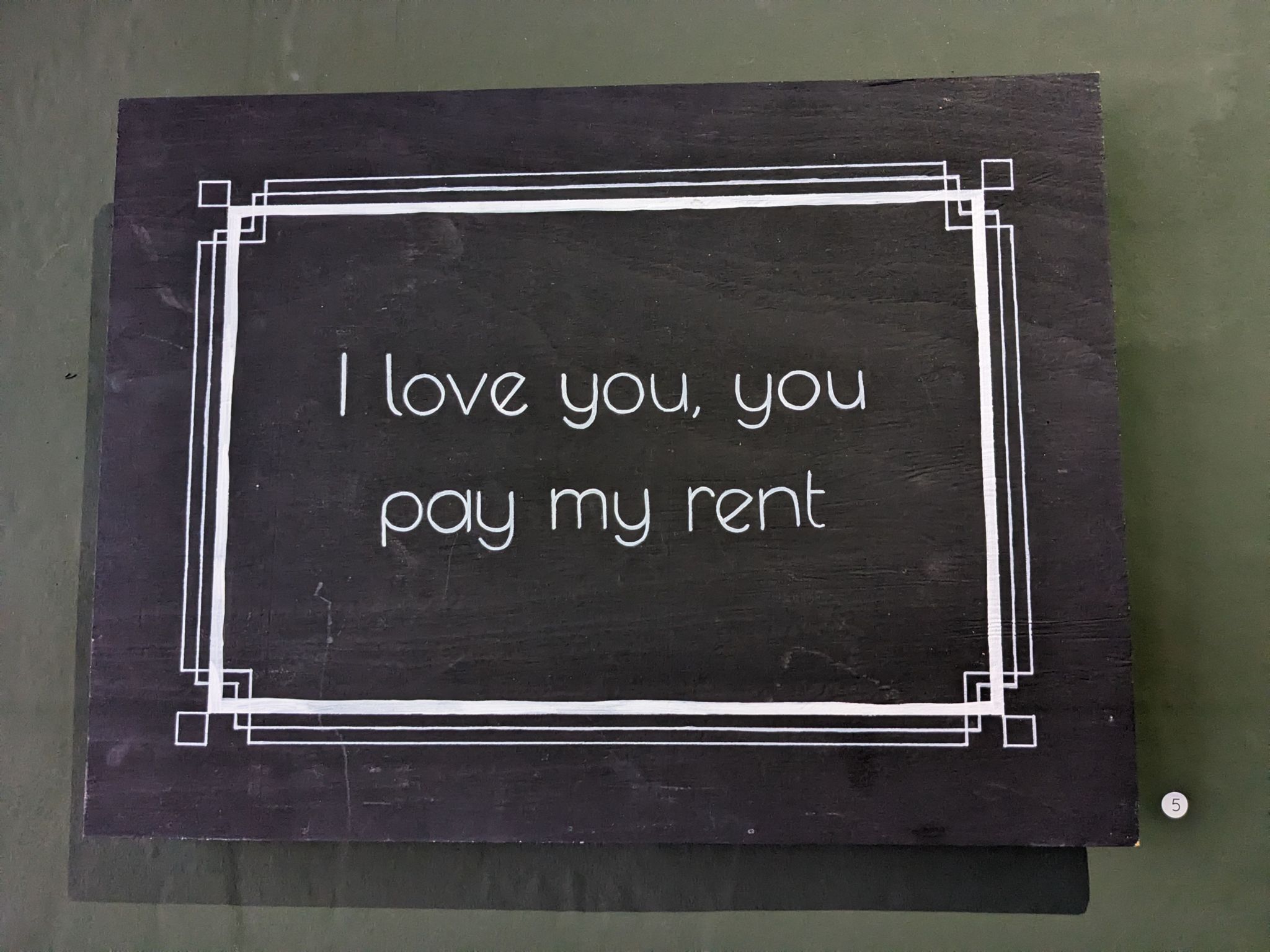 a sign reading "I love you, you pay my rent"