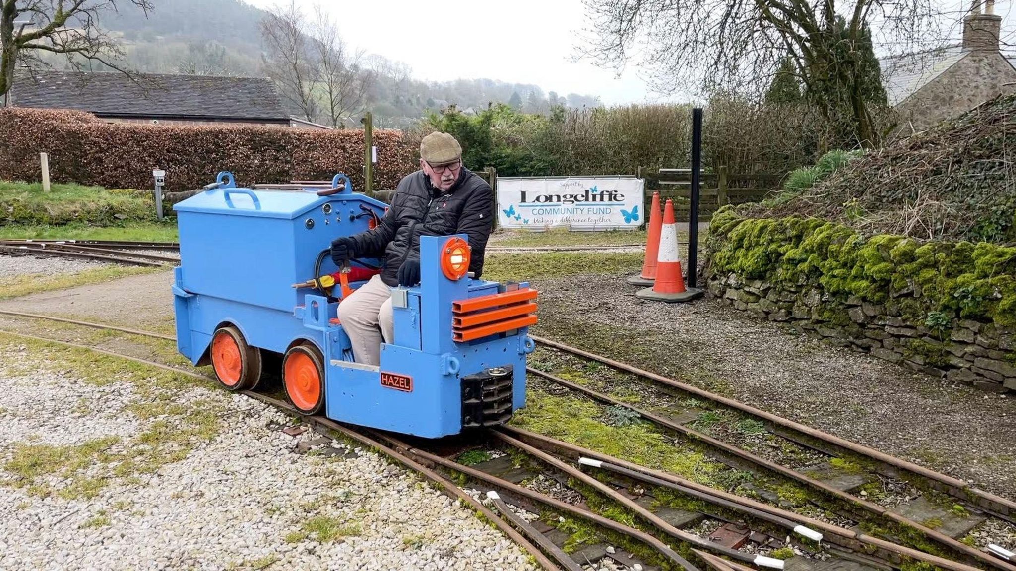 Jim is sitting on a battery powered loco on the tracks at Steeple Grange Light Railway