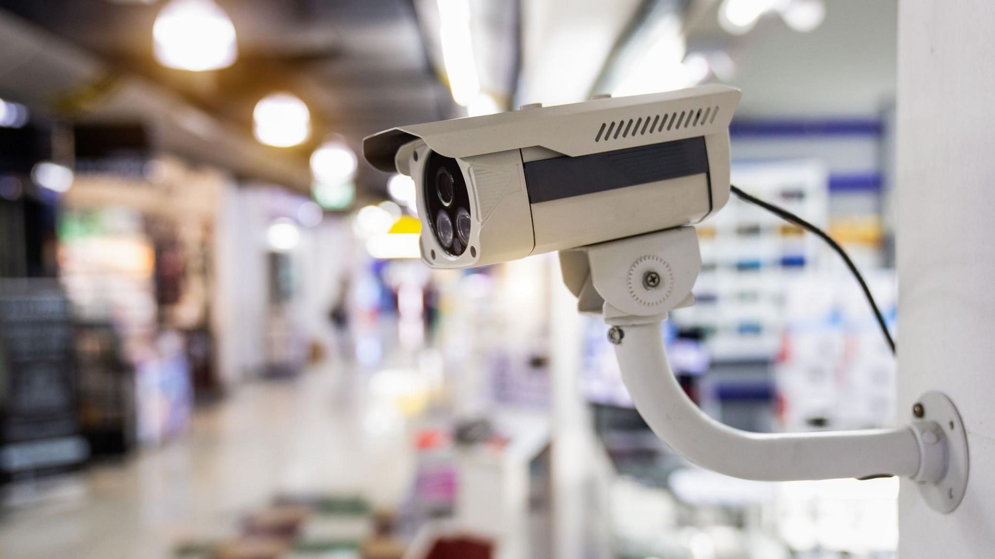 CCTV camera in the foreground with a blurred shopping centre seen in the background