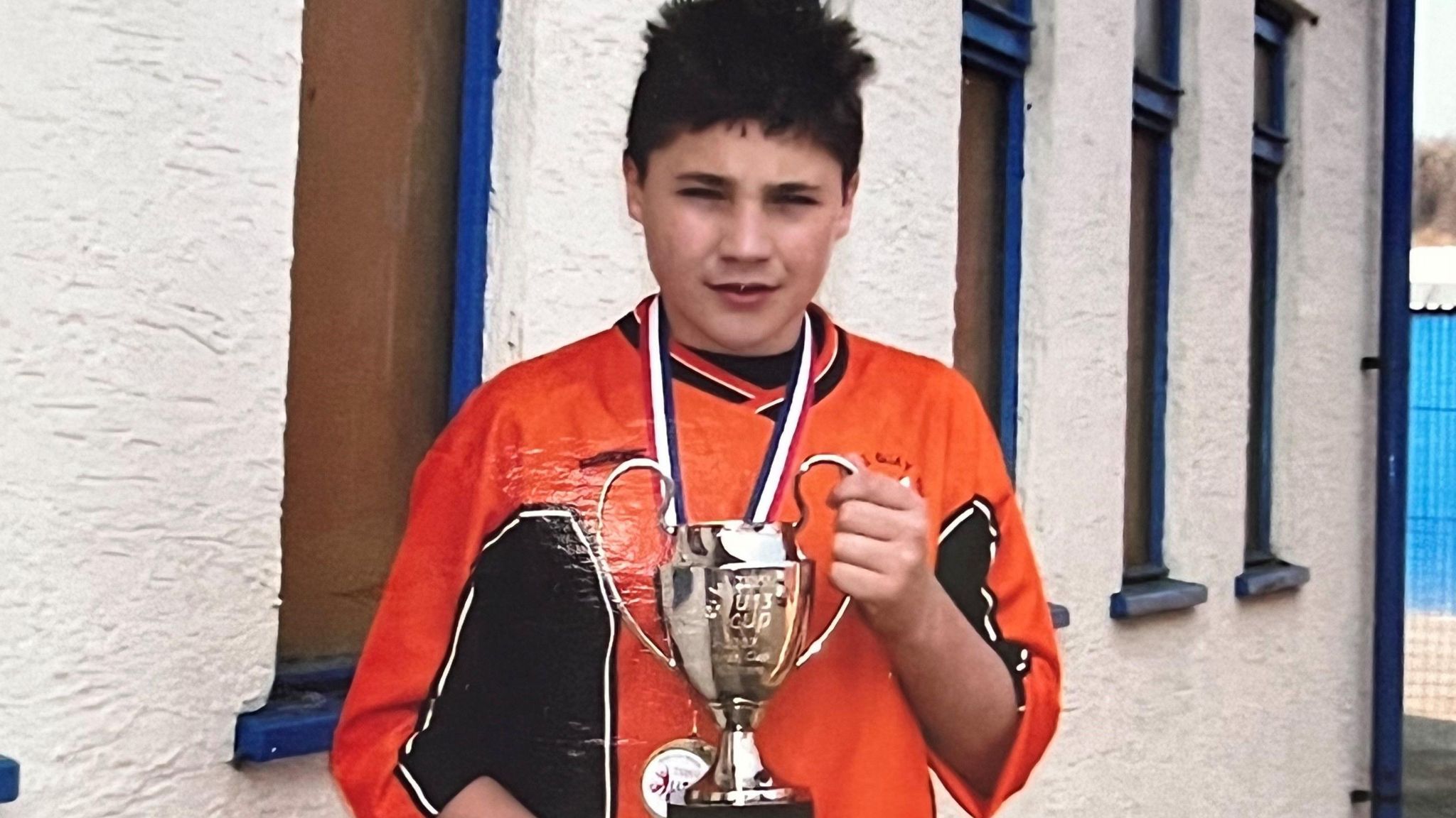 Jamie Wynn holding a football trophy as a boy