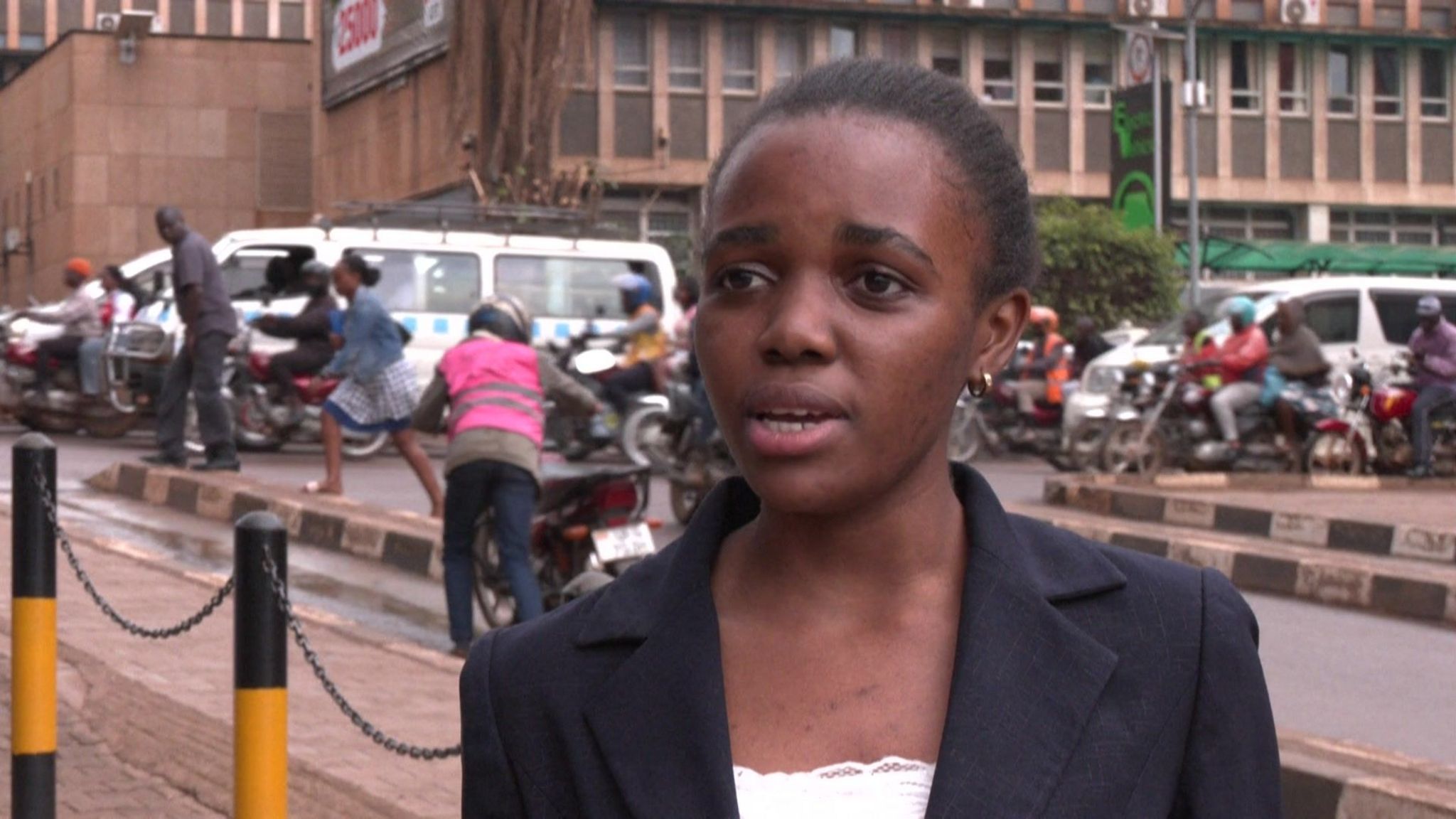 A young woman in a coat stands in a street