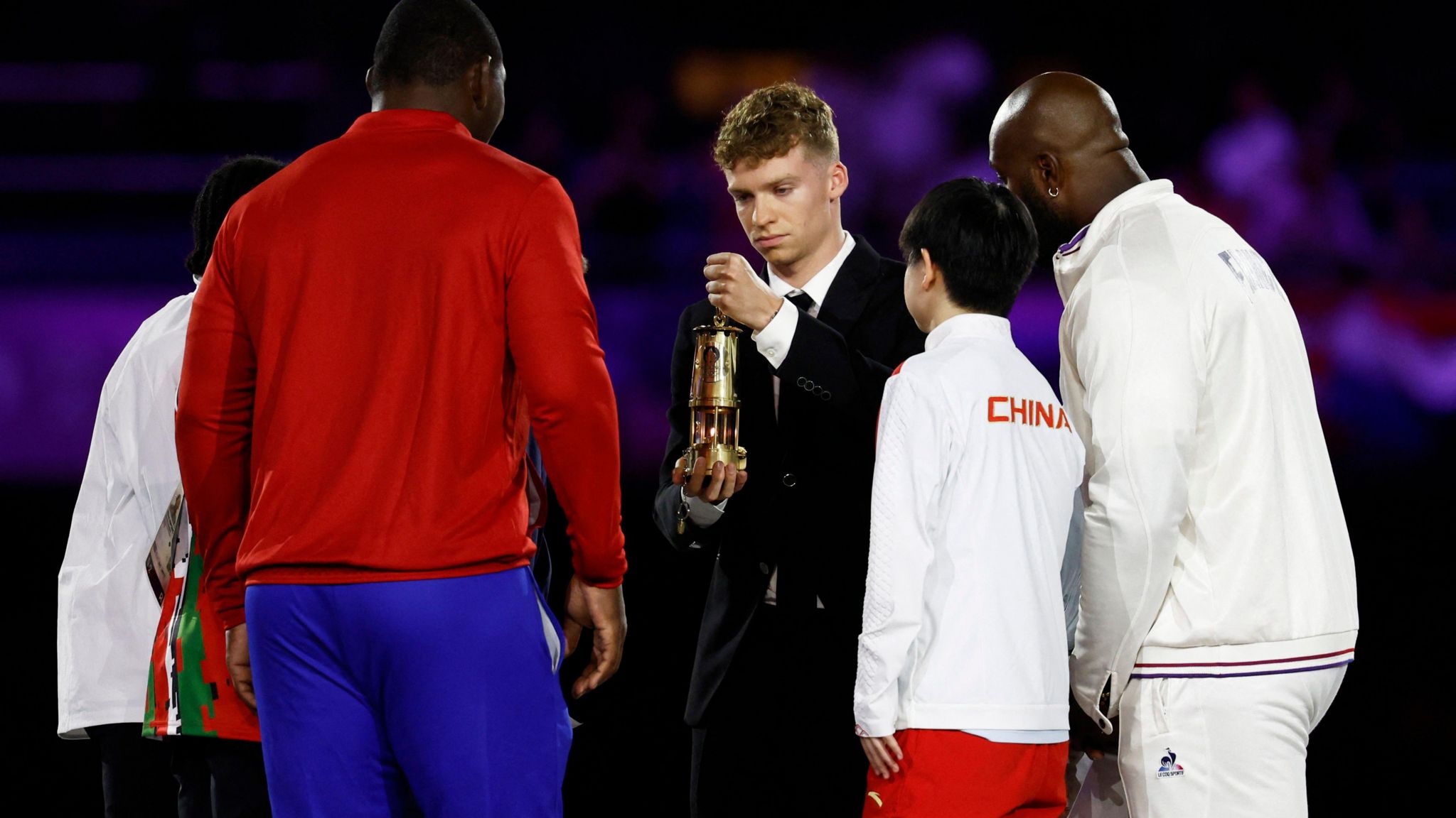 Leon Marchand carries the Olympic flame into Stade de France