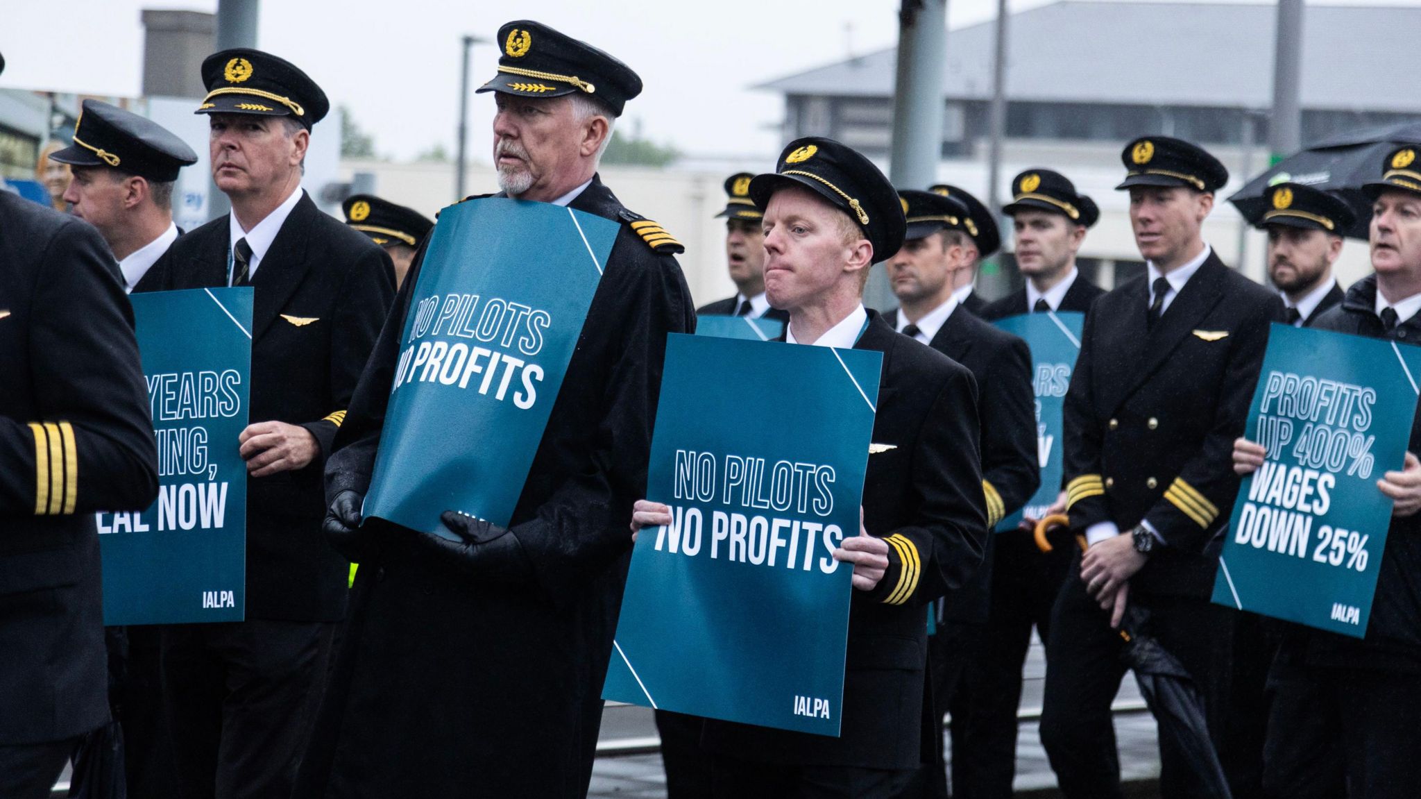 A number of striking Aer Lingus pilots standing outside Dublin airport holding placards
