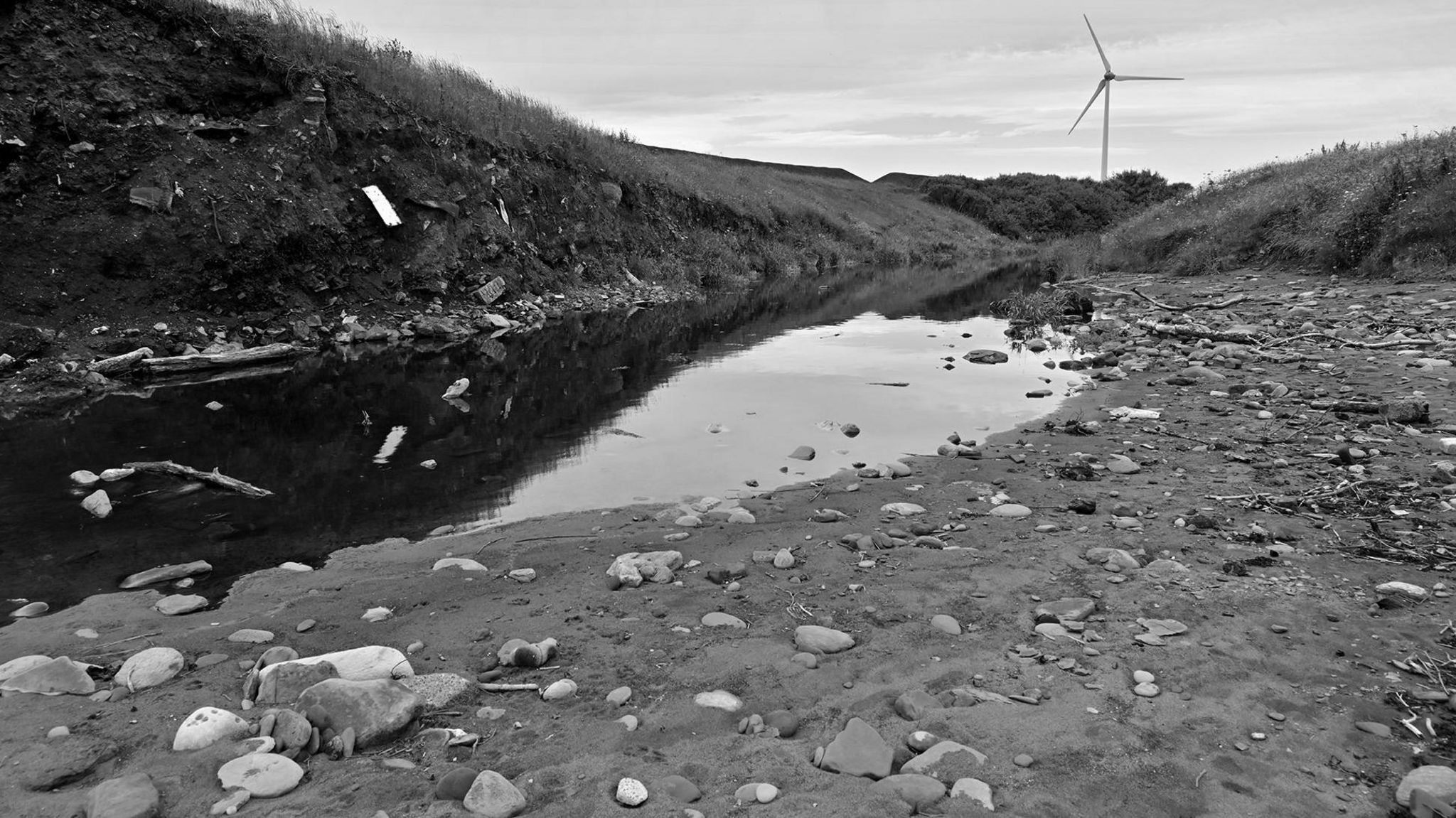 An industrial scene with a wind turbine in the distance 