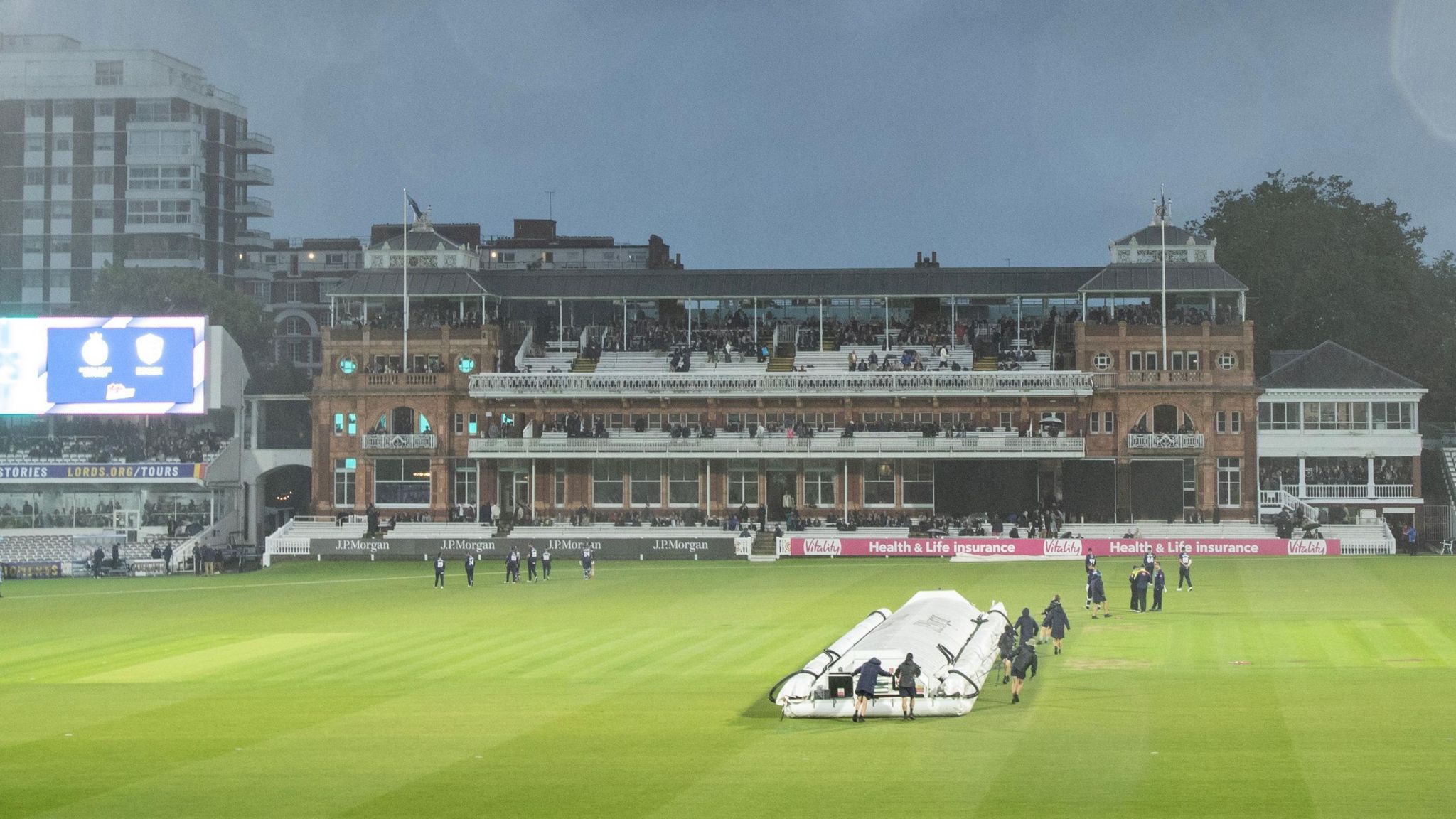 Groundstaff bring on the covers at a wet Lord's