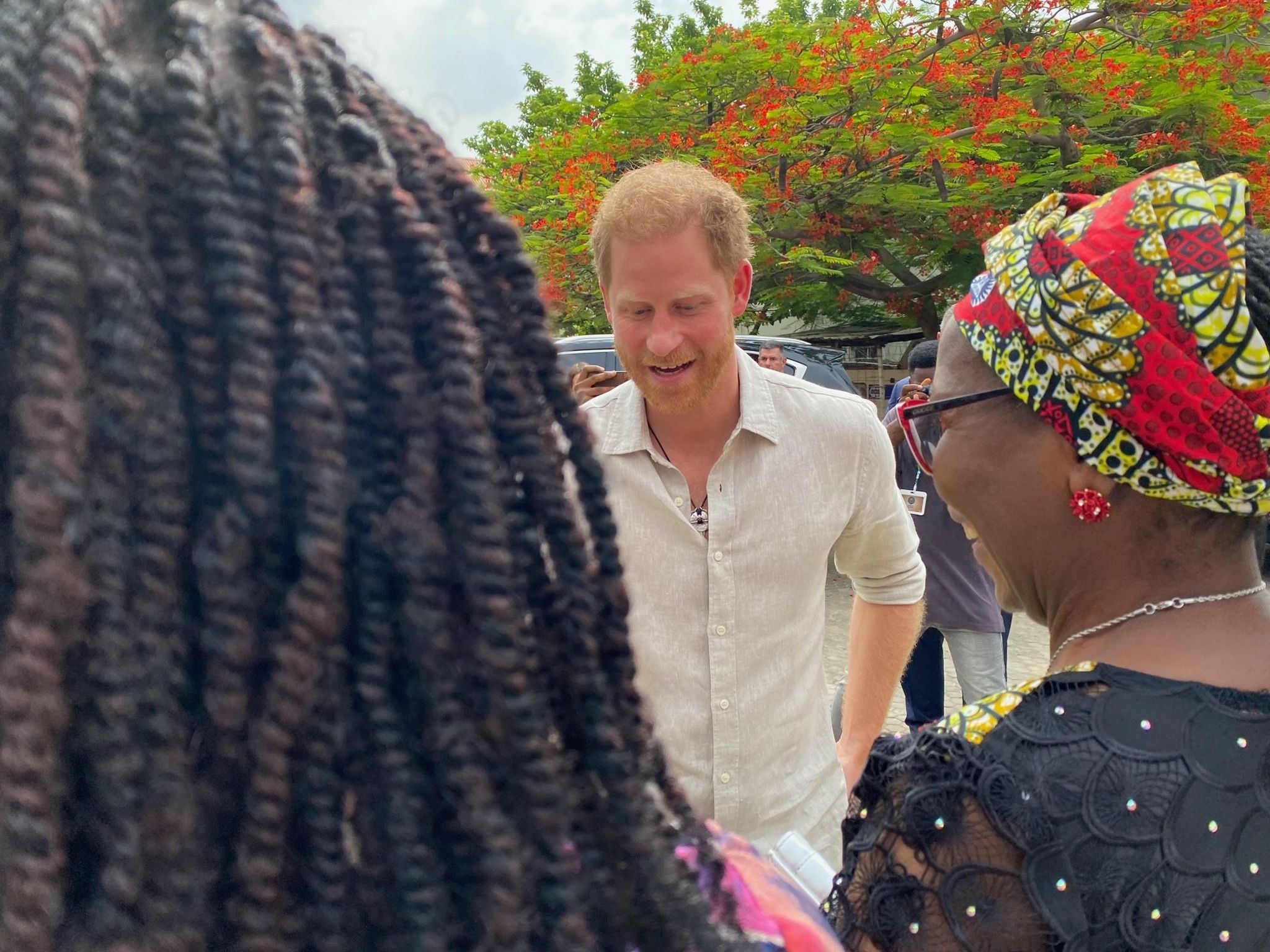 Prince Harry greeting two people at a school in Abuja