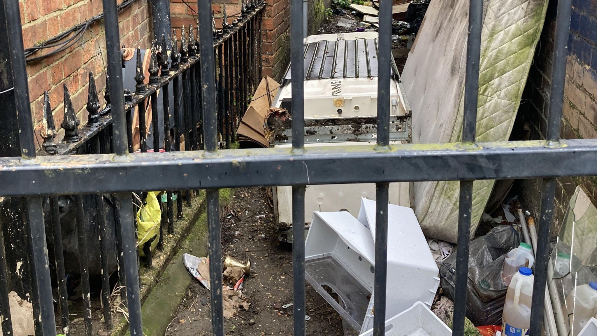 An old mattress and other household items left in a back alley