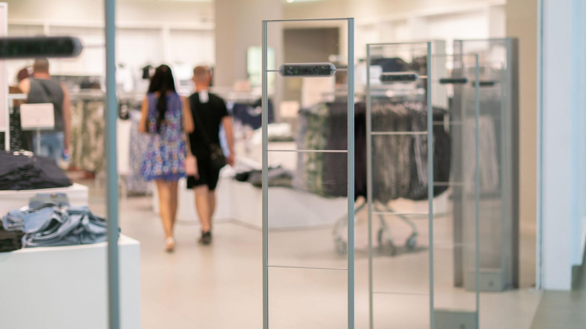 A security scanner at a shop entrance with two women in the background